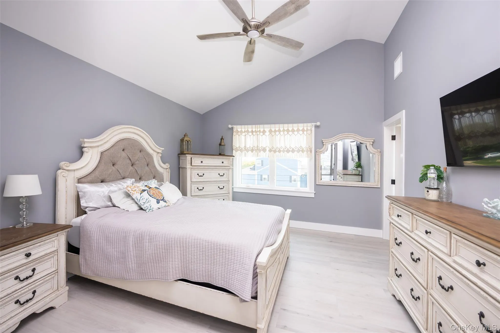 Bedroom with light wood-style flooring, high vaulted ceiling, and a ceiling fan Bedroom with light wood-style flooring, high vaulted ceiling, and a ceiling fan