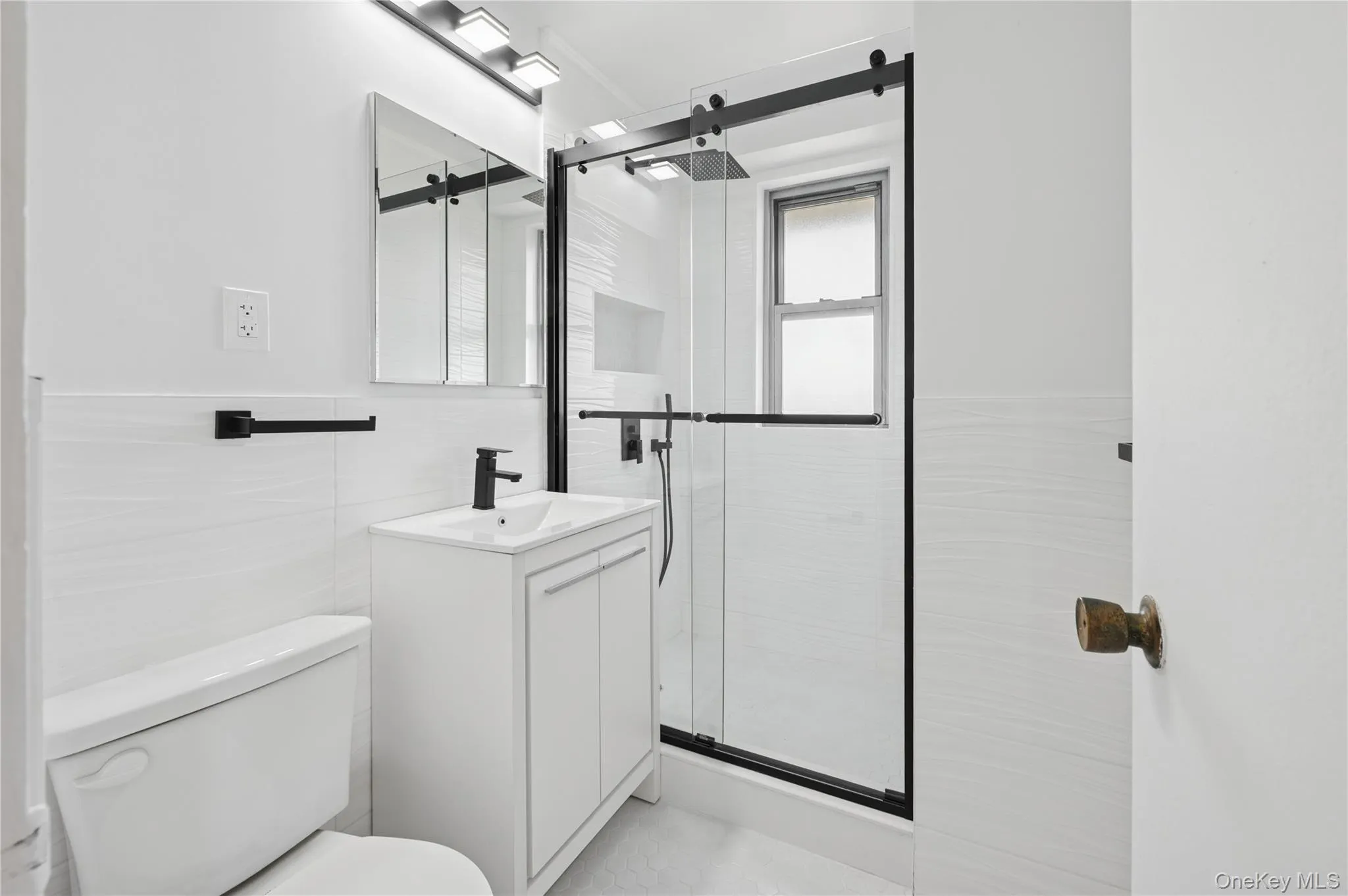 Bathroom featuring vanity, a stall shower, and tile walls Bathroom featuring vanity, a stall shower, and tile walls
