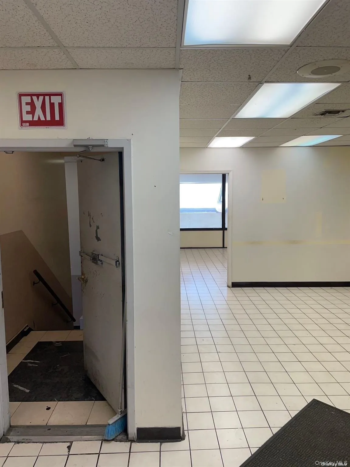 Hall featuring a paneled ceiling, an upstairs landing, and light tile patterned floors Hall featuring a paneled ceiling, an upstairs landing, and light tile patterned floors