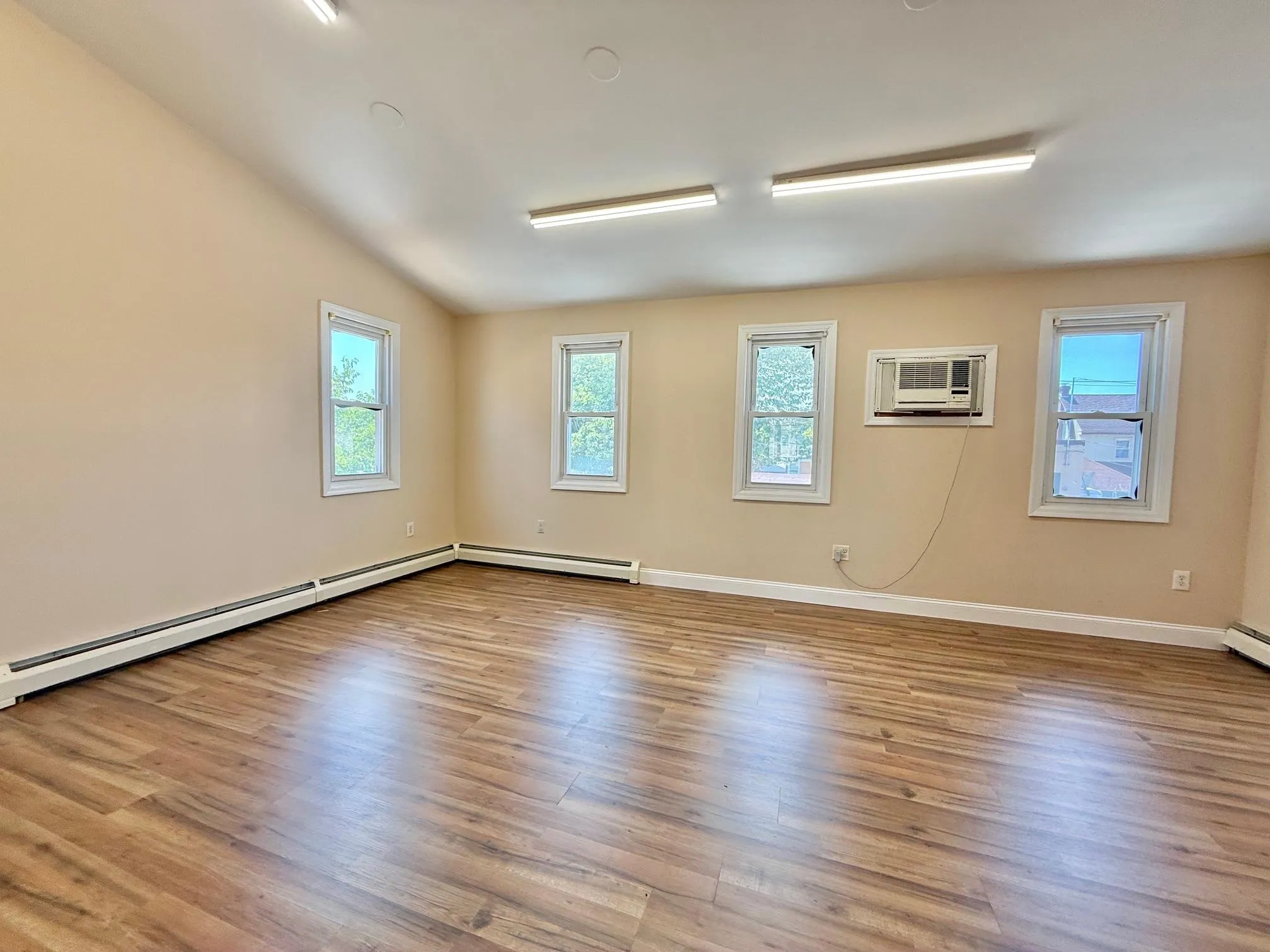 Spare room with wood finished floors, a wall unit AC, a baseboard radiator, and lofted ceiling Spare room with wood finished floors, a wall unit AC, a baseboard radiator, and lofted ceiling