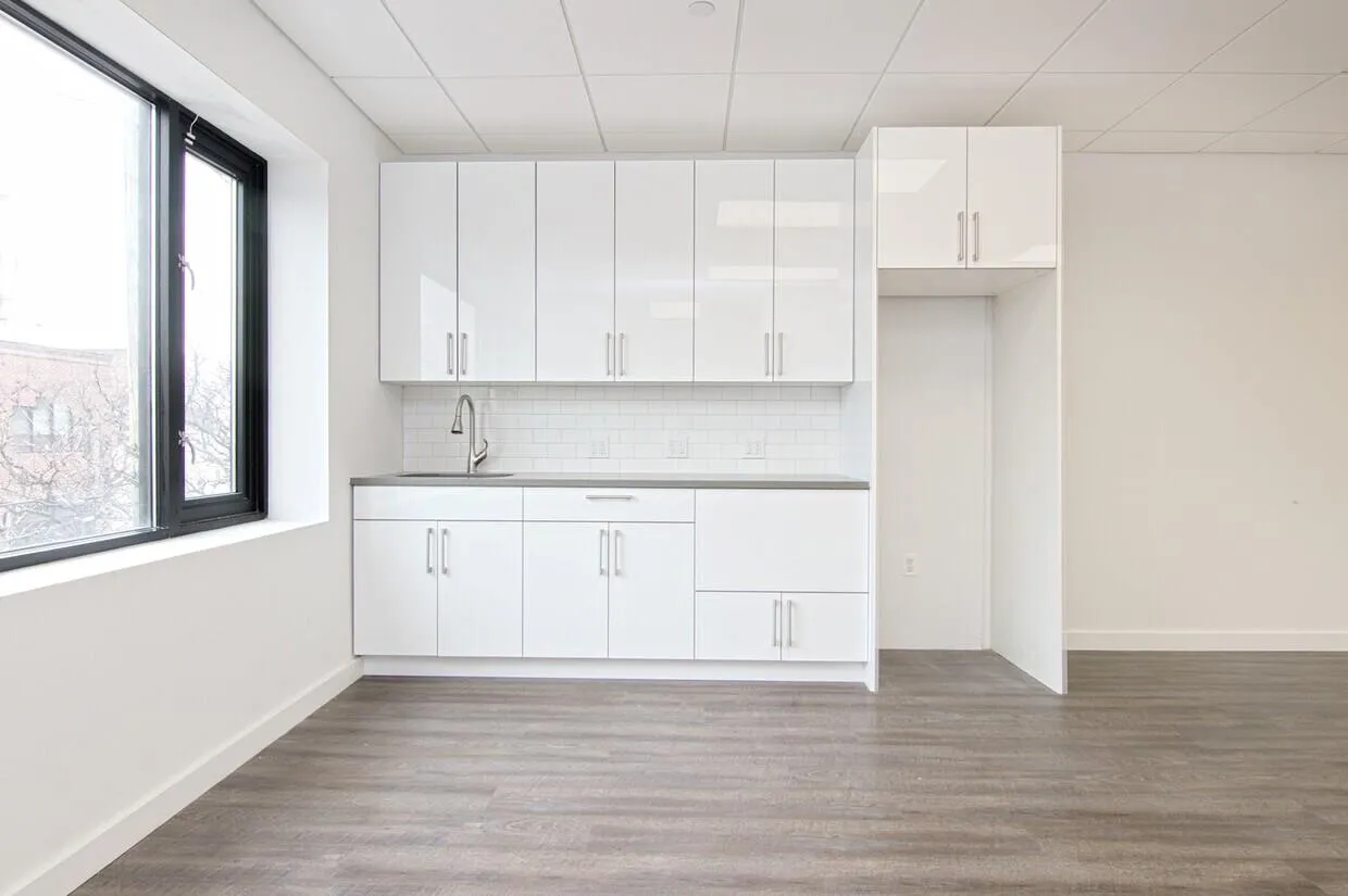 Kitchen featuring white cabinets, tasteful backsplash, light wood-style flooring, and a drop ceiling Kitchen featuring white cabinets, tasteful backsplash, light wood-style flooring, and a drop ceiling