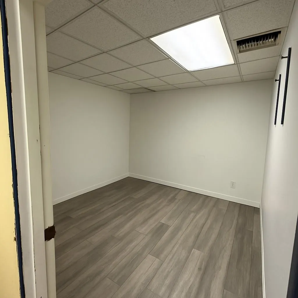 Empty room with a drop ceiling and dark wood-style floors Empty room with a drop ceiling and dark wood-style floors