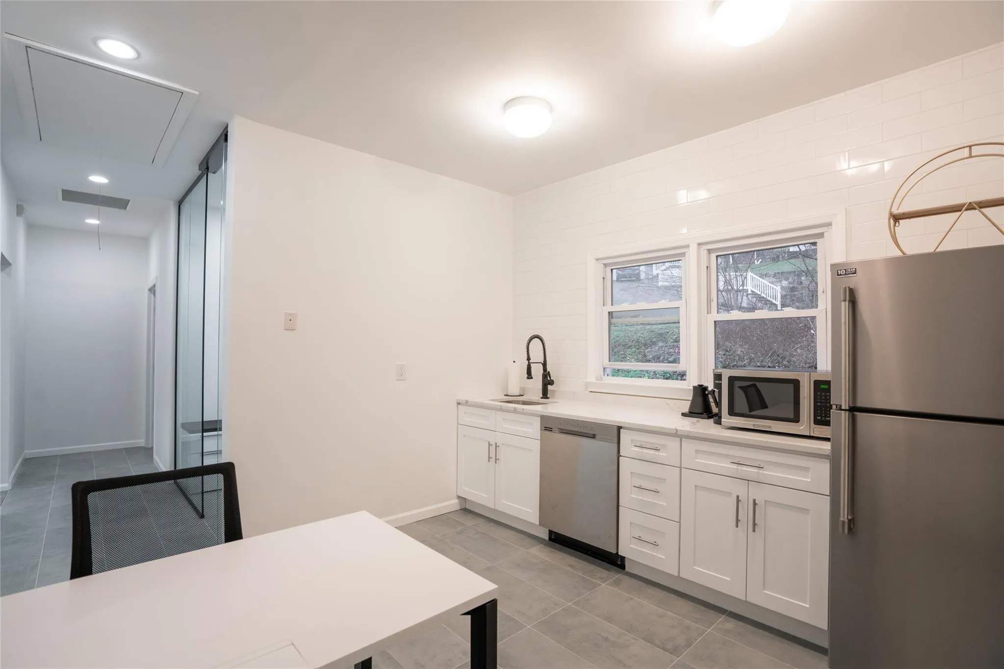 Kitchen with appliances with stainless steel finishes, light tile patterned flooring, light countertops, white cabinets, and tasteful backsplash Kitchen with appliances with stainless steel finishes, light tile patterned flooring, light countertops, white cabinets, and tasteful backsplash