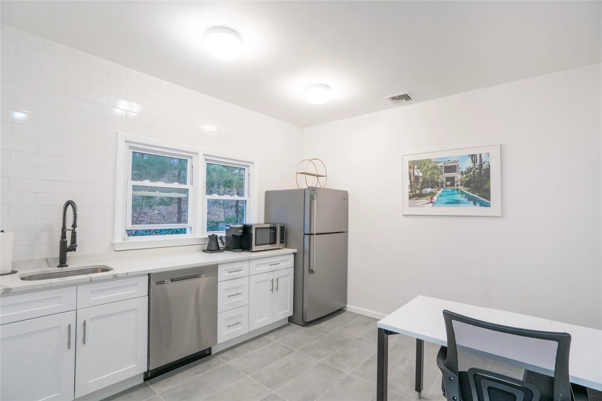 Kitchen featuring stainless steel appliances, white cabinets, light tile patterned flooring, and light stone countertops Kitchen featuring stainless steel appliances, white cabinets, light tile patterned flooring, and light stone countertops