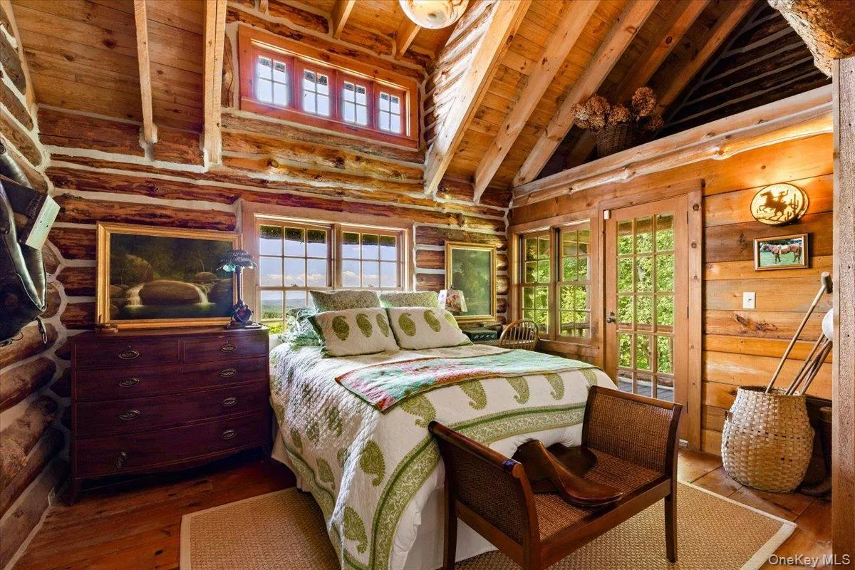 Bedroom with a wooden ceiling with exposed beams, high vaulted ceiling, wood-type flooring, multiple windows, and rustic walls Bedroom with a wooden ceiling with exposed beams, high vaulted ceiling, wood-type flooring, multiple windows, and rustic walls