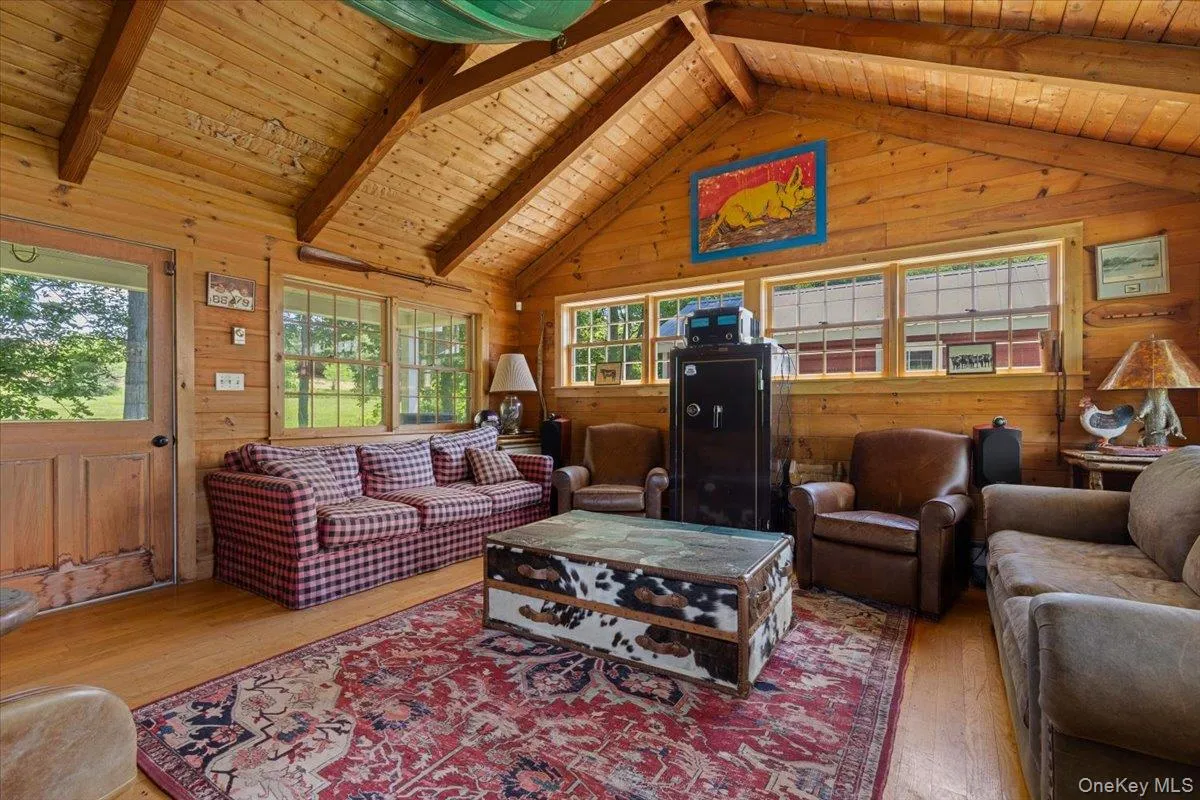 Living area with wood-type flooring, plenty of natural light, wood walls, and wooden ceiling Living area with wood-type flooring, plenty of natural light, wood walls, and wooden ceiling