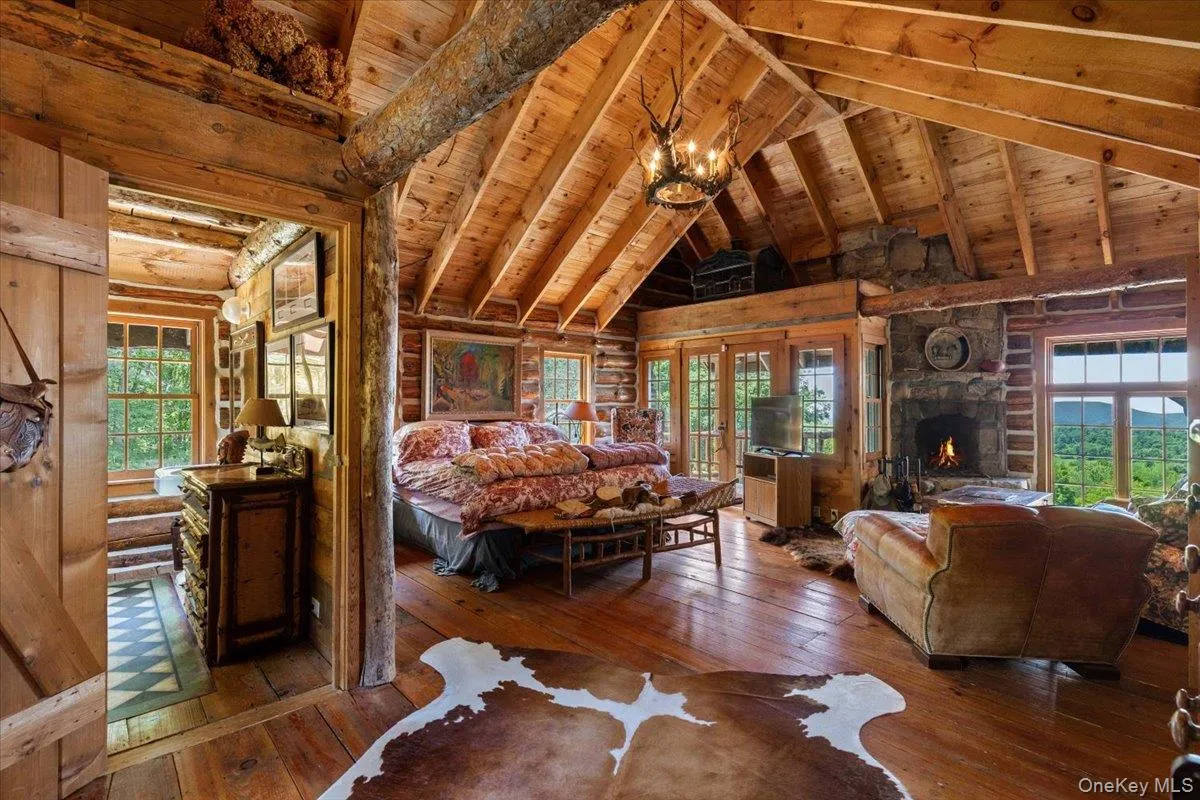 Bedroom featuring hardwood / wood-style flooring, multiple windows, a wood ceiling with exposed beams, a fireplace, and high vaulted ceiling Bedroom featuring hardwood / wood-style flooring, multiple windows, a wood ceiling with exposed beams, a fireplace, and high vaulted ceiling