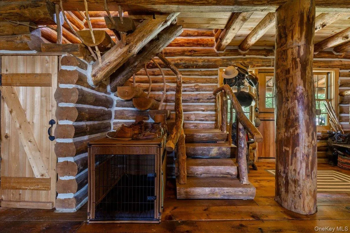 Stairway featuring log walls, hardwood / wood-style floors, and a wooden ceiling with exposed beams Stairway featuring log walls, hardwood / wood-style floors, and a wooden ceiling with exposed beams