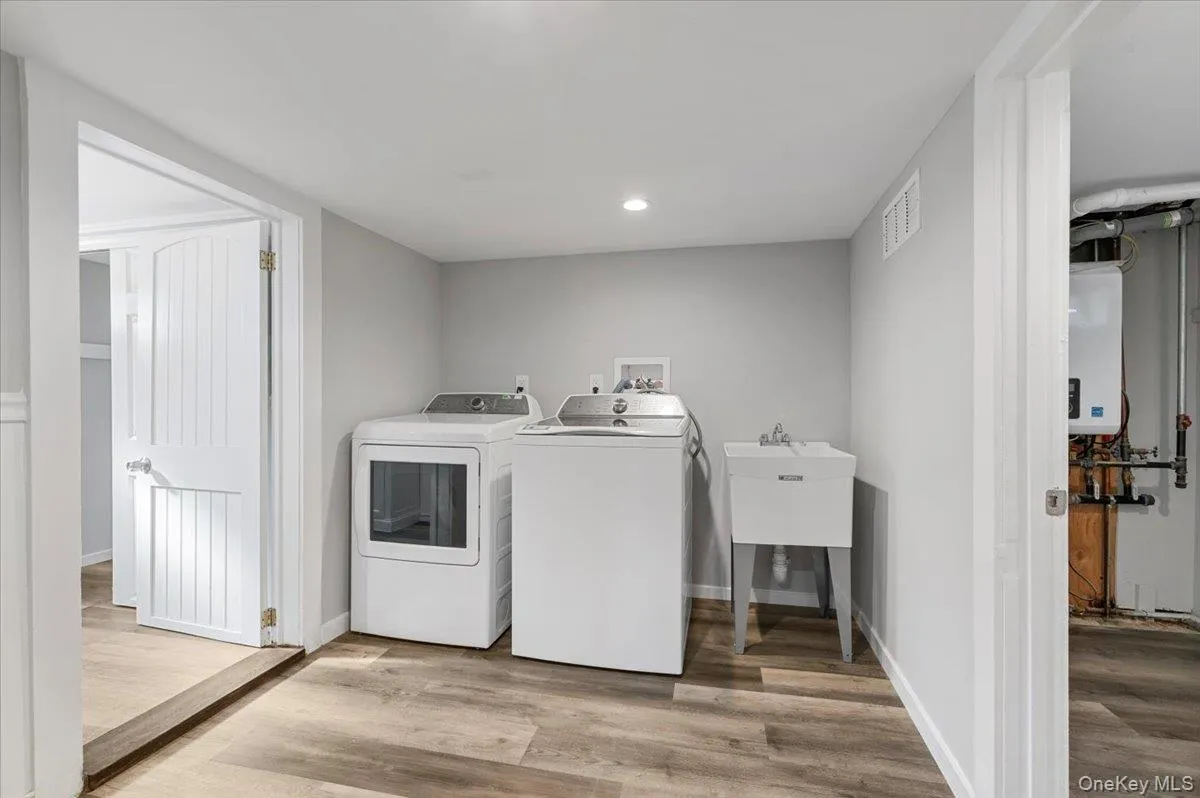 Laundry room with light wood-style flooring, recessed lighting, independent washer and dryer, and water heater Laundry room with light wood-style flooring, recessed lighting, independent washer and dryer, and water heater