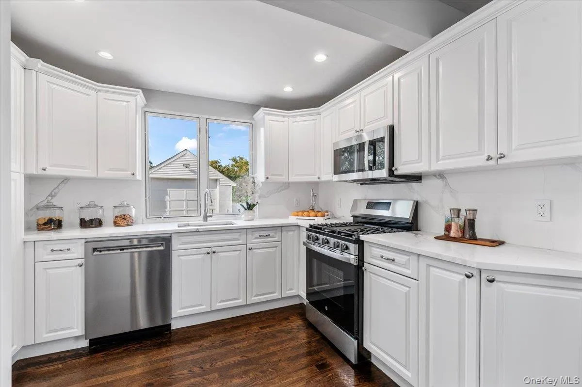 Kitchen with white cabinetry, appliances with stainless steel finishes, dark wood-type flooring, and recessed lighting Kitchen with white cabinetry, appliances with stainless steel finishes, dark wood-type flooring, and recessed lighting