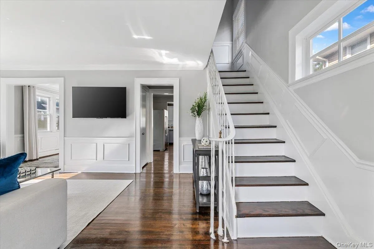 Stairs featuring a decorative wall, ornamental molding, wood finished floors, and a wainscoted wall Stairs featuring a decorative wall, ornamental molding, wood finished floors, and a wainscoted wall