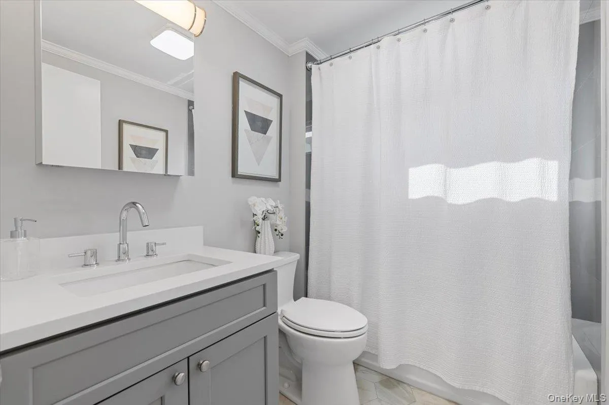 Full bath featuring ornamental molding, shower / bath combination with curtain, and vanity Full bath featuring ornamental molding, shower / bath combination with curtain, and vanity