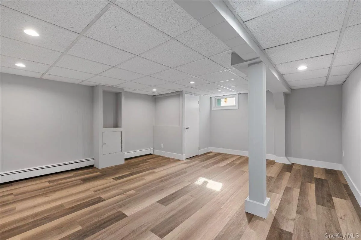 Basement featuring light wood-type flooring, recessed lighting, a baseboard heating unit, and a paneled ceiling Basement featuring light wood-type flooring, recessed lighting, a baseboard heating unit, and a paneled ceiling