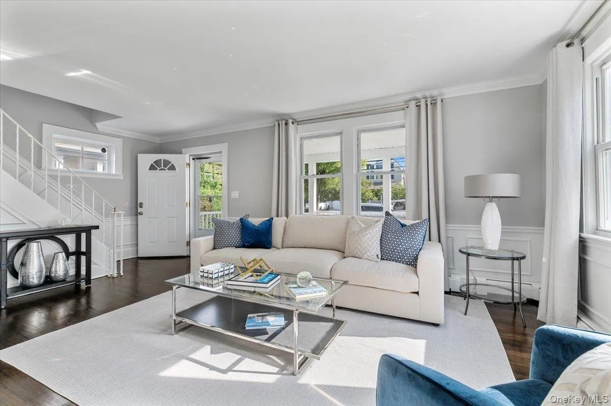 Living room featuring wainscoting, stairway, a decorative wall, dark wood-type flooring, and crown molding Living room featuring wainscoting, stairway, a decorative wall, dark wood-type flooring, and crown molding
