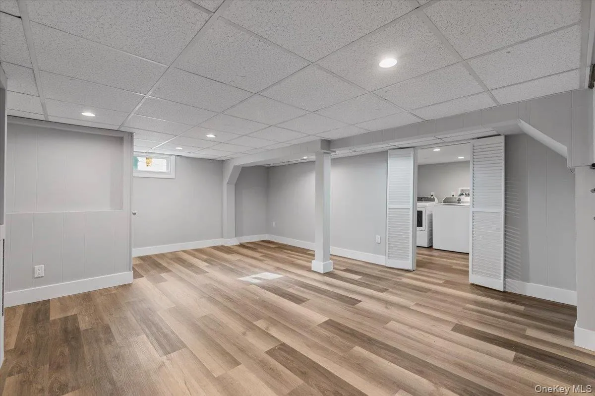 Below grade area with recessed lighting, light wood finished floors, washer and dryer, and a drop ceiling Below grade area with recessed lighting, light wood finished floors, washer and dryer, and a drop ceiling