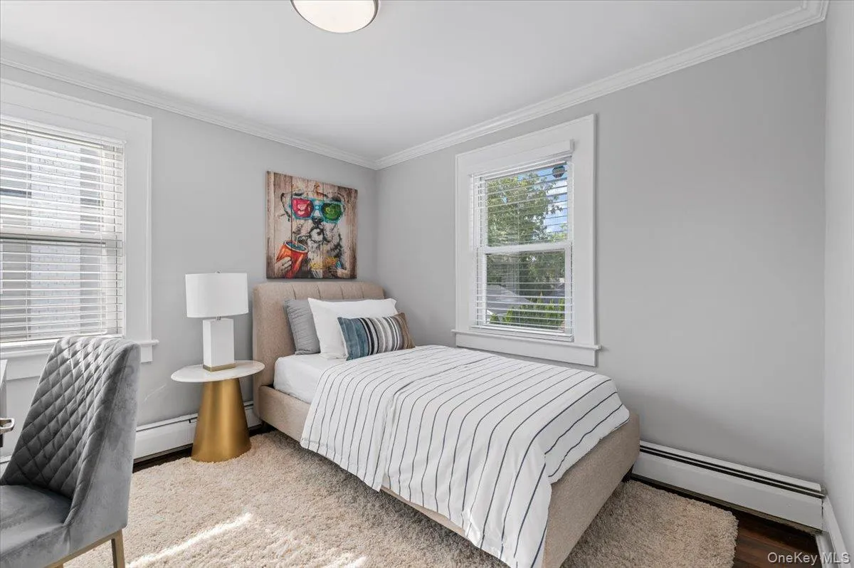 Bedroom featuring ornamental molding, a baseboard radiator, and wood finished floors Bedroom featuring ornamental molding, a baseboard radiator, and wood finished floors
