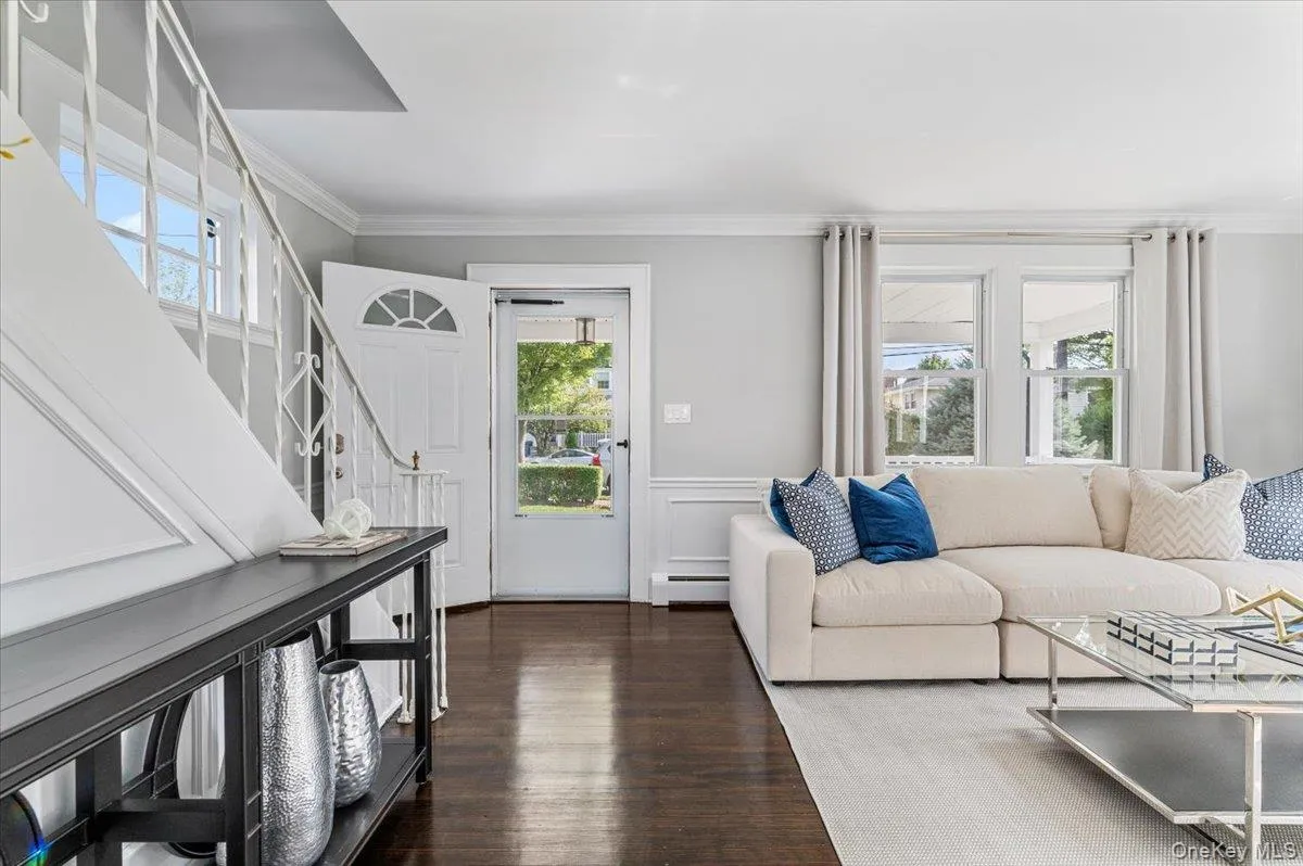 Living area with healthy amount of natural light, crown molding, a wainscoted wall, dark wood finished floors, and a decorative wall Living area with healthy amount of natural light, crown molding, a wainscoted wall, dark wood finished floors, and a decorative wall