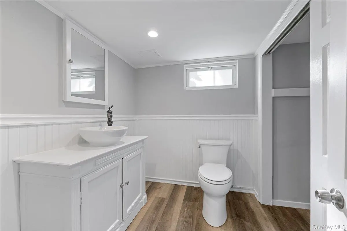 Bathroom featuring crown molding, light wood-type flooring, vanity, wainscoting, and recessed lighting Bathroom featuring crown molding, light wood-type flooring, vanity, wainscoting, and recessed lighting