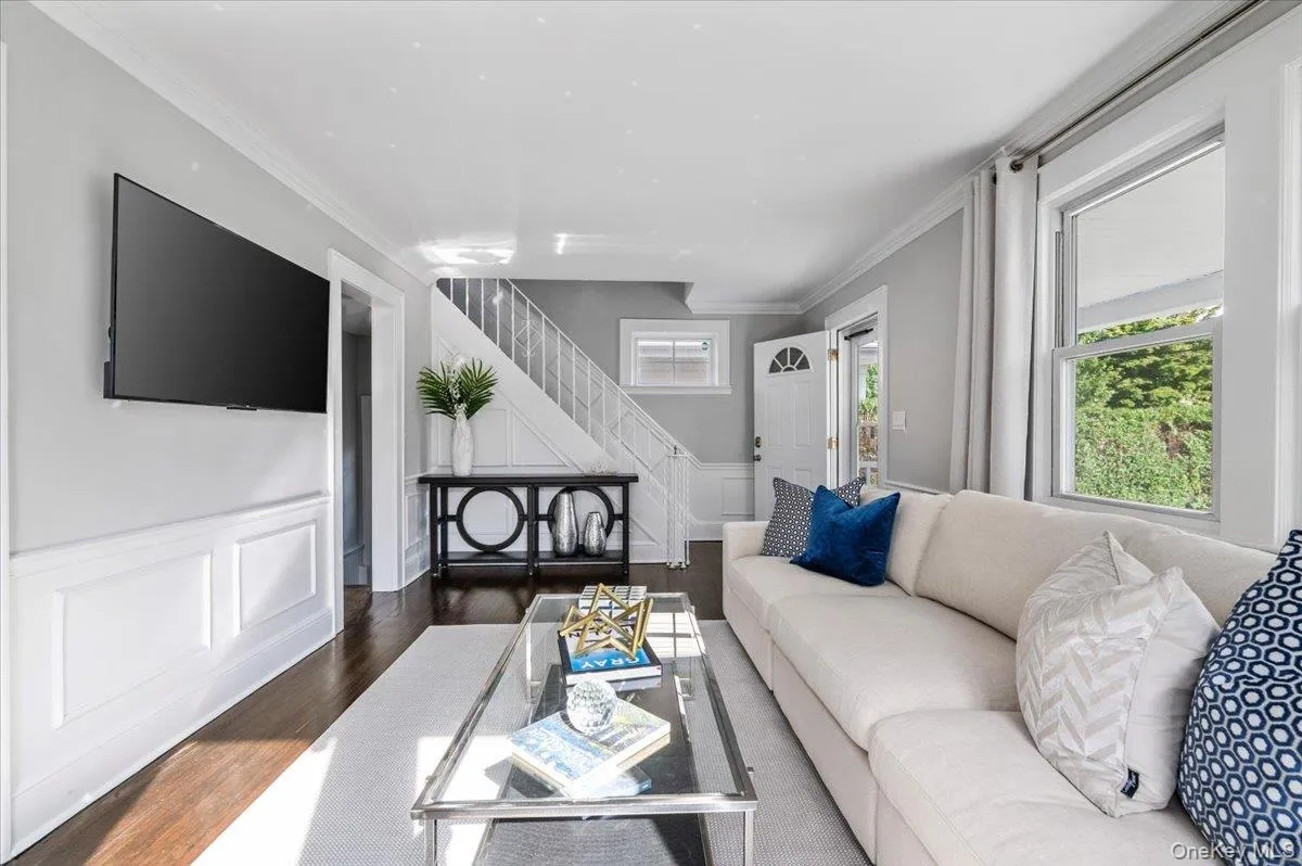 Living room featuring crown molding, a decorative wall, wainscoting, wood finished floors, and healthy amount of natural light Living room featuring crown molding, a decorative wall, wainscoting, wood finished floors, and healthy amount of natural light