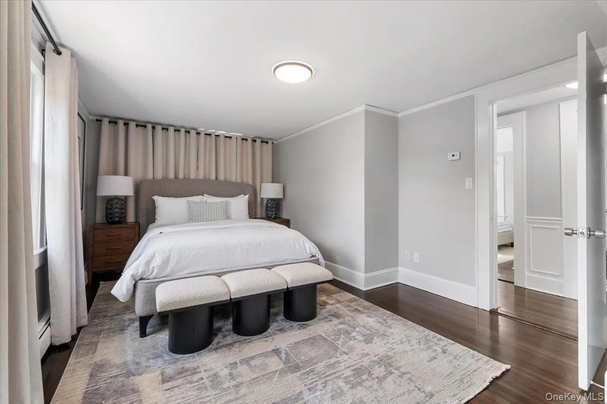 Bedroom featuring dark wood finished floors, ornamental molding, and baseboard heating Bedroom featuring dark wood finished floors, ornamental molding, and baseboard heating