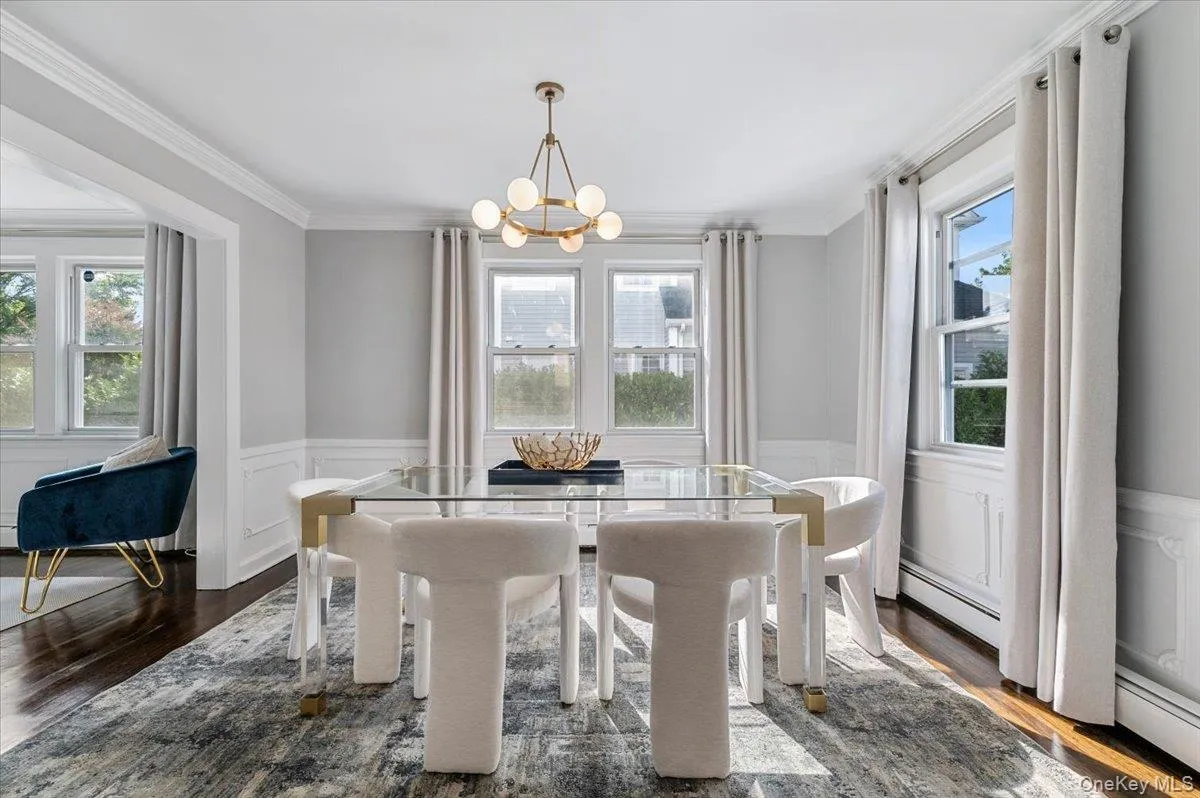 Dining area featuring a wainscoted wall, dark wood-type flooring, a decorative wall, ornamental molding, and baseboard heating Dining area featuring a wainscoted wall, dark wood-type flooring, a decorative wall, ornamental molding, and baseboard heating