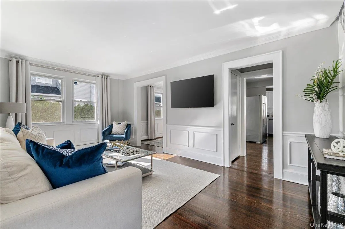 Living room featuring dark wood finished floors, a decorative wall, and crown molding Living room featuring dark wood finished floors, a decorative wall, and crown molding