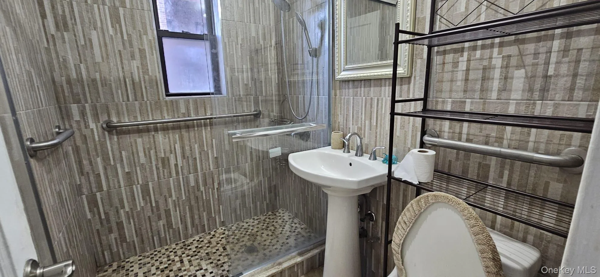 Full bath featuring a tile shower and tile walls Full bath featuring a tile shower and tile walls