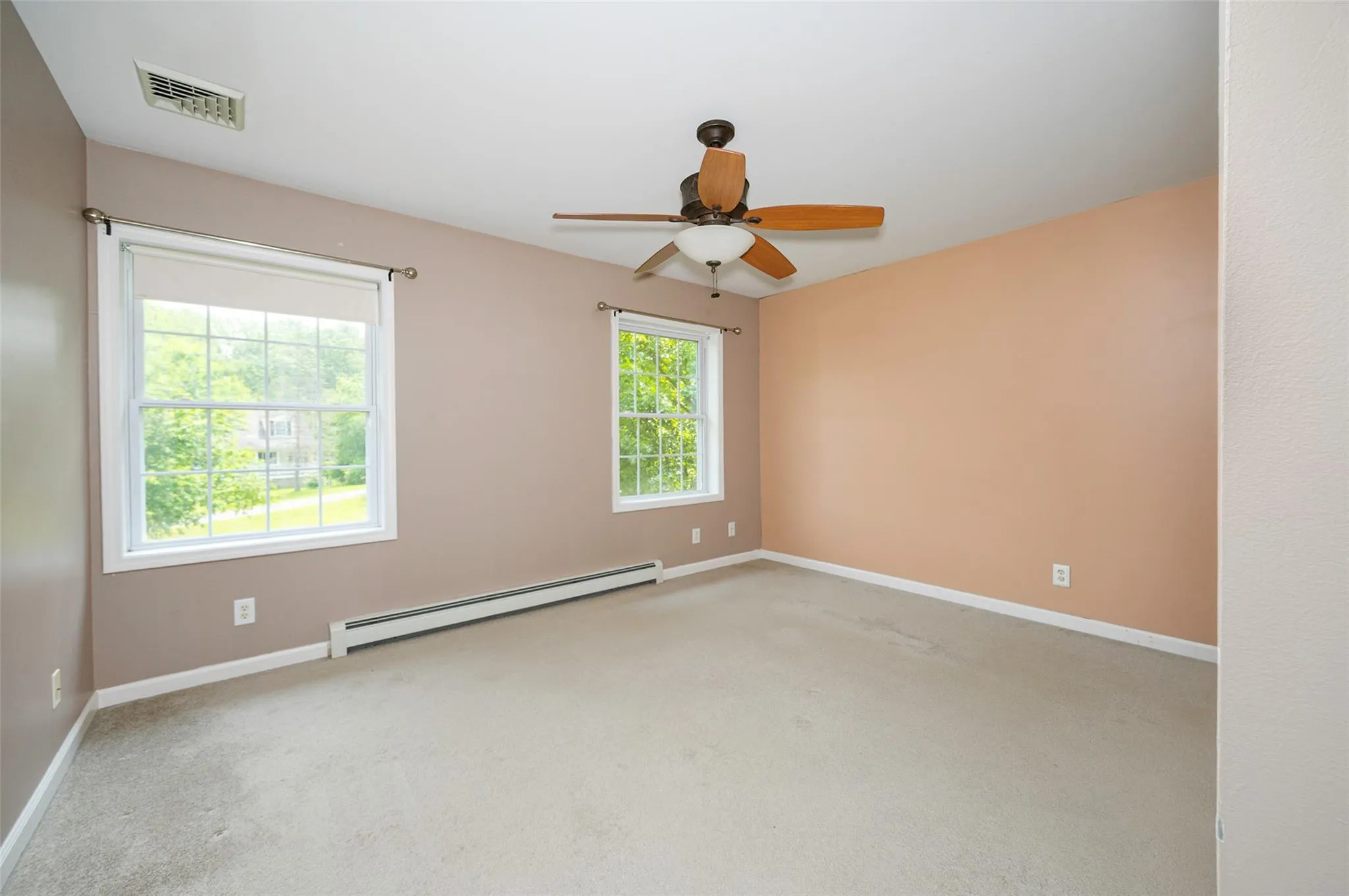 Carpeted empty room with baseboard heating and a ceiling fan Carpeted empty room with baseboard heating and a ceiling fan