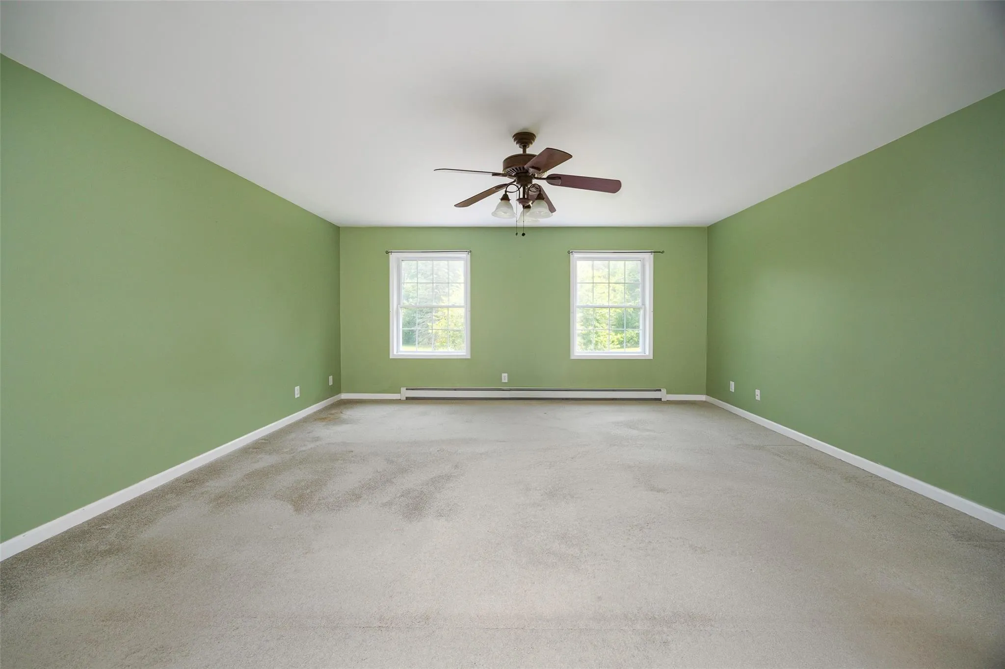 Spare room featuring a baseboard radiator, a ceiling fan, and carpet floors Spare room featuring a baseboard radiator, a ceiling fan, and carpet floors