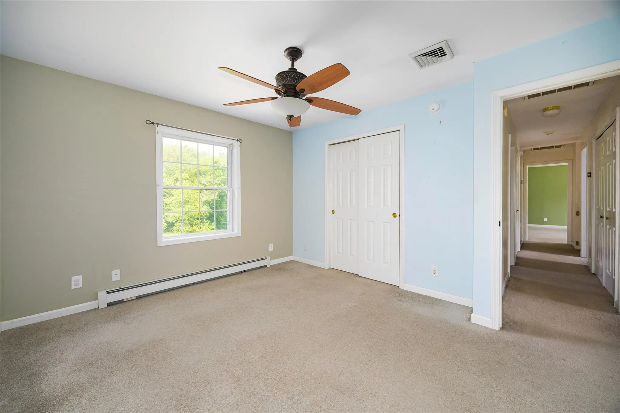 Unfurnished bedroom featuring a baseboard radiator, carpet, a closet, and ceiling fan Unfurnished bedroom featuring a baseboard radiator, carpet, a closet, and ceiling fan