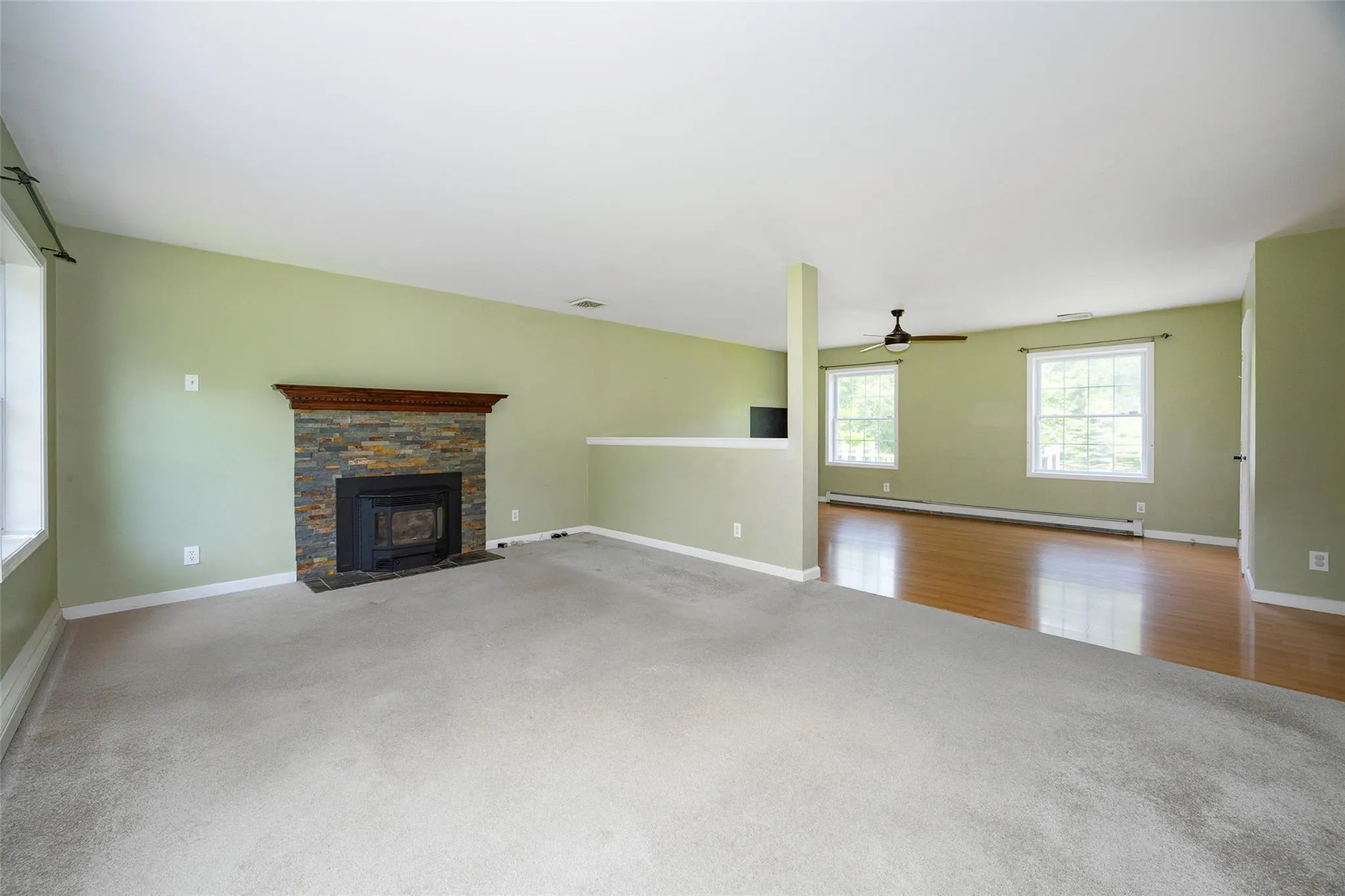 Unfurnished living room featuring carpet flooring, a baseboard radiator, and a ceiling fan Unfurnished living room featuring carpet flooring, a baseboard radiator, and a ceiling fan