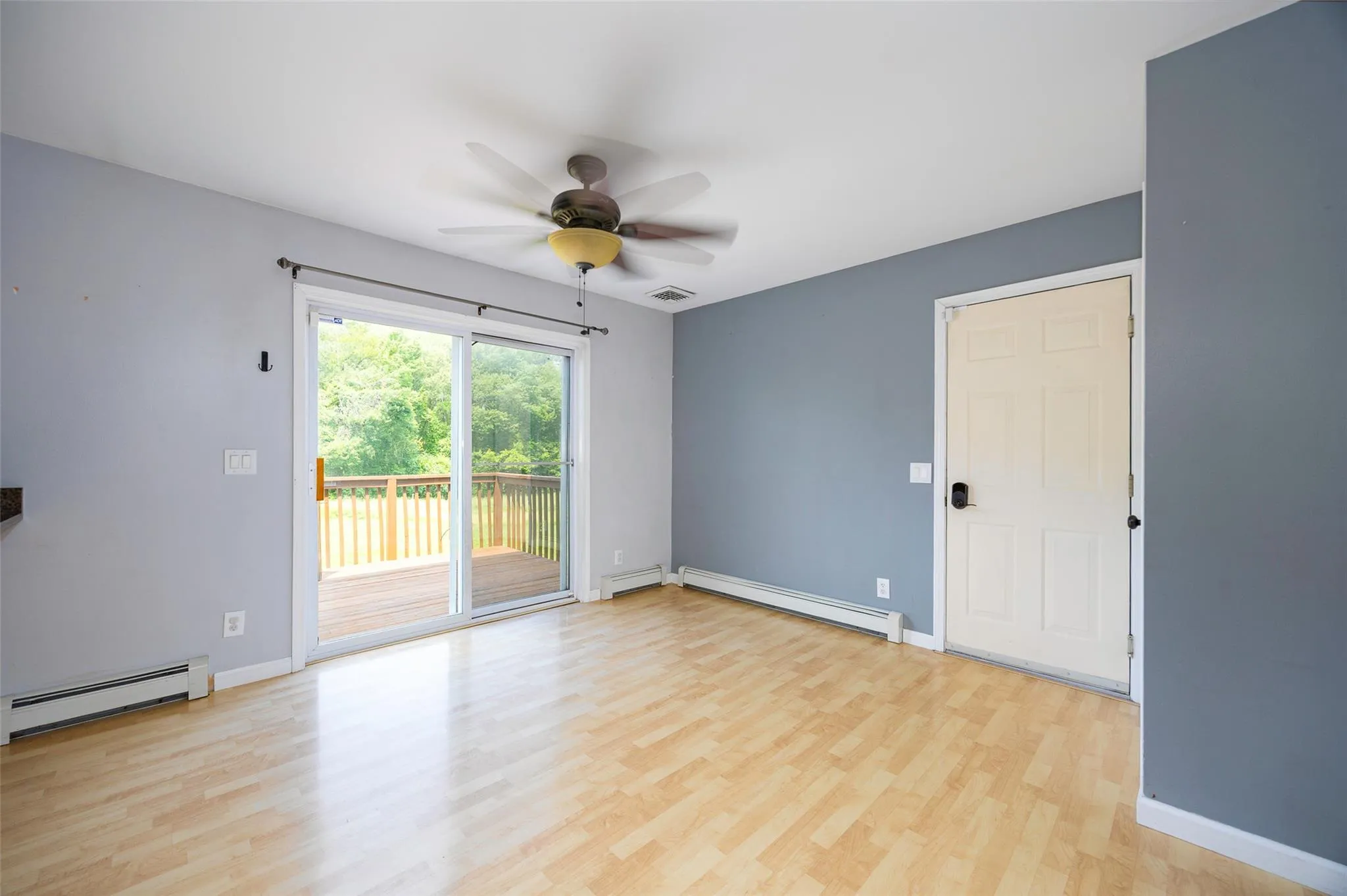 Empty room featuring a baseboard heating unit, ceiling fan, and light wood finished floors Empty room featuring a baseboard heating unit, ceiling fan, and light wood finished floors