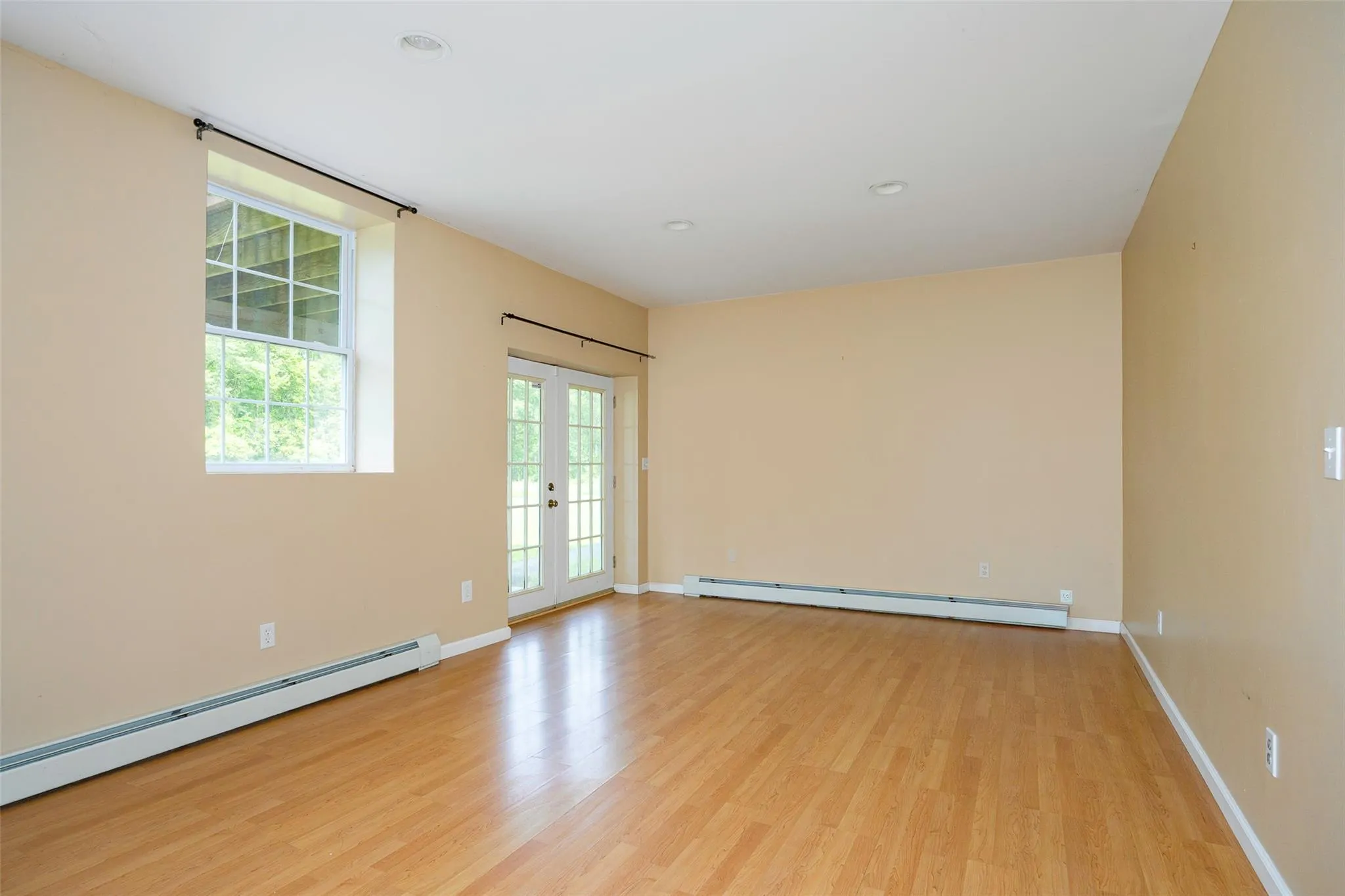 Spare room featuring a baseboard heating unit, light wood-type flooring, recessed lighting, and french doors Spare room featuring a baseboard heating unit, light wood-type flooring, recessed lighting, and french doors