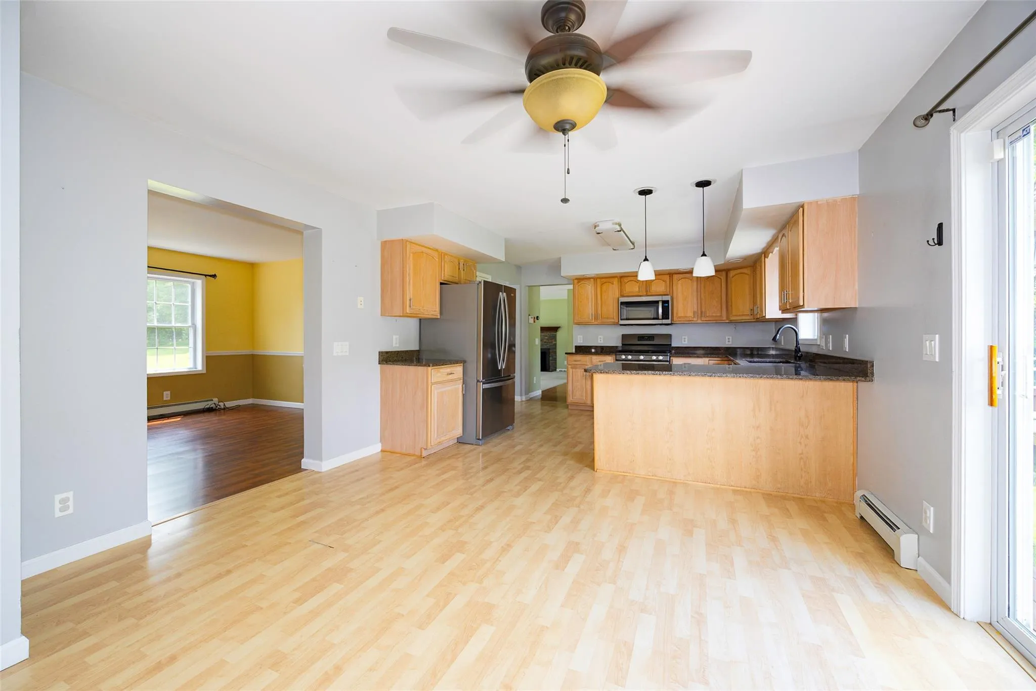 Kitchen with stainless steel appliances, a baseboard heating unit, light wood-style flooring, and a peninsula Kitchen with stainless steel appliances, a baseboard heating unit, light wood-style flooring, and a peninsula