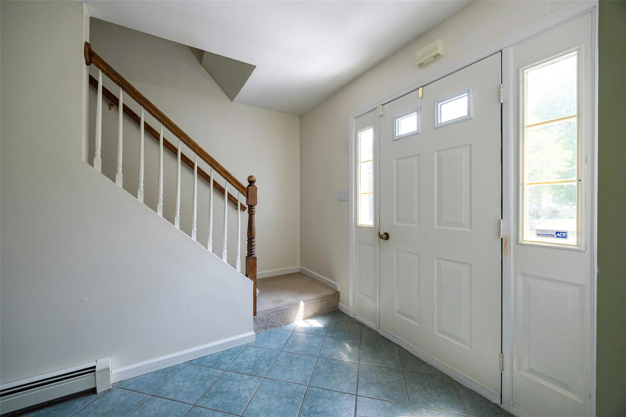 Entryway with a baseboard heating unit, stairway, tile patterned flooring, and carpet flooring Entryway with a baseboard heating unit, stairway, tile patterned flooring, and carpet flooring