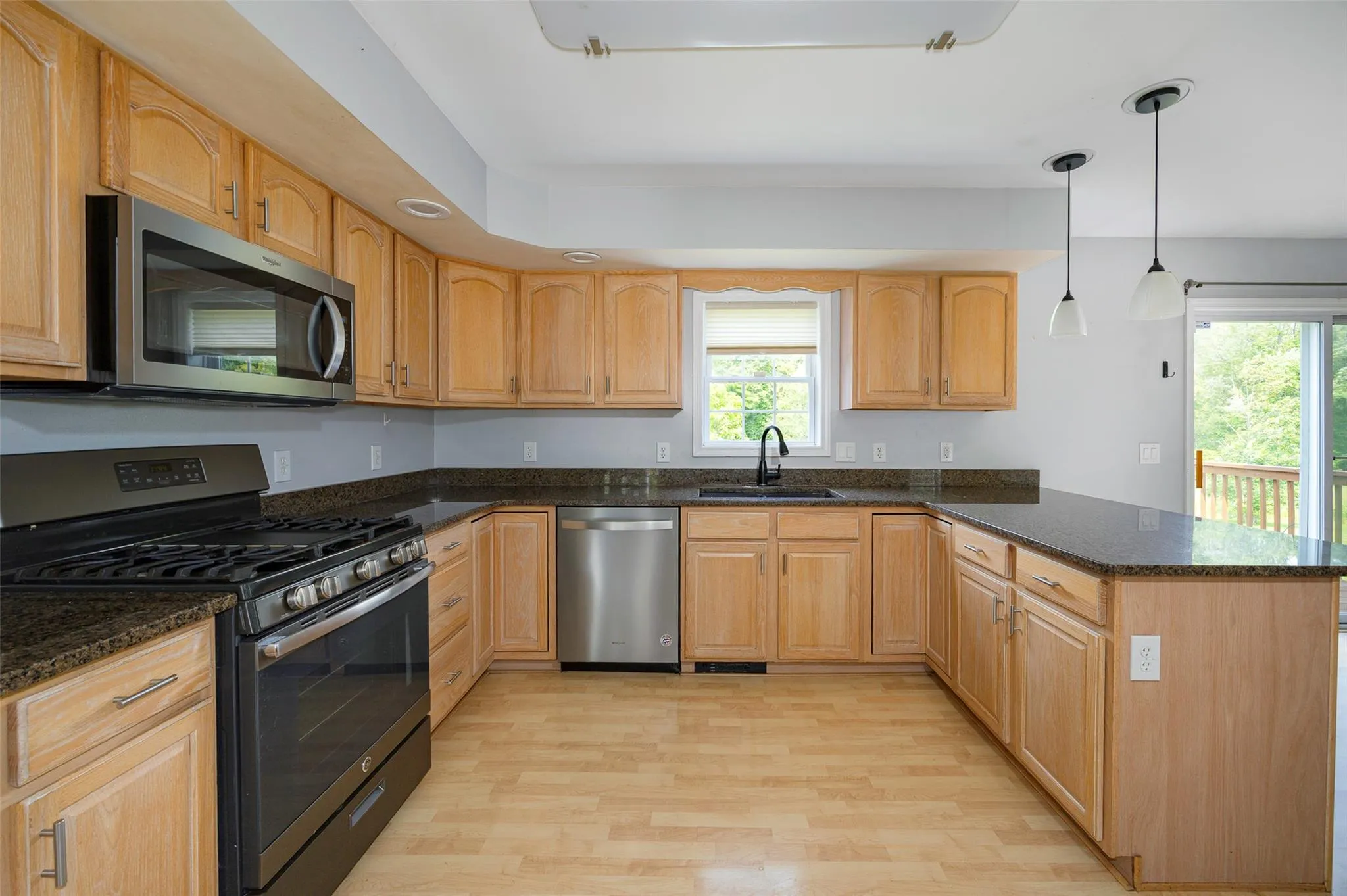 Kitchen featuring appliances with stainless steel finishes, a peninsula, light wood-style flooring, and plenty of natural light Kitchen featuring appliances with stainless steel finishes, a peninsula, light wood-style flooring, and plenty of natural light