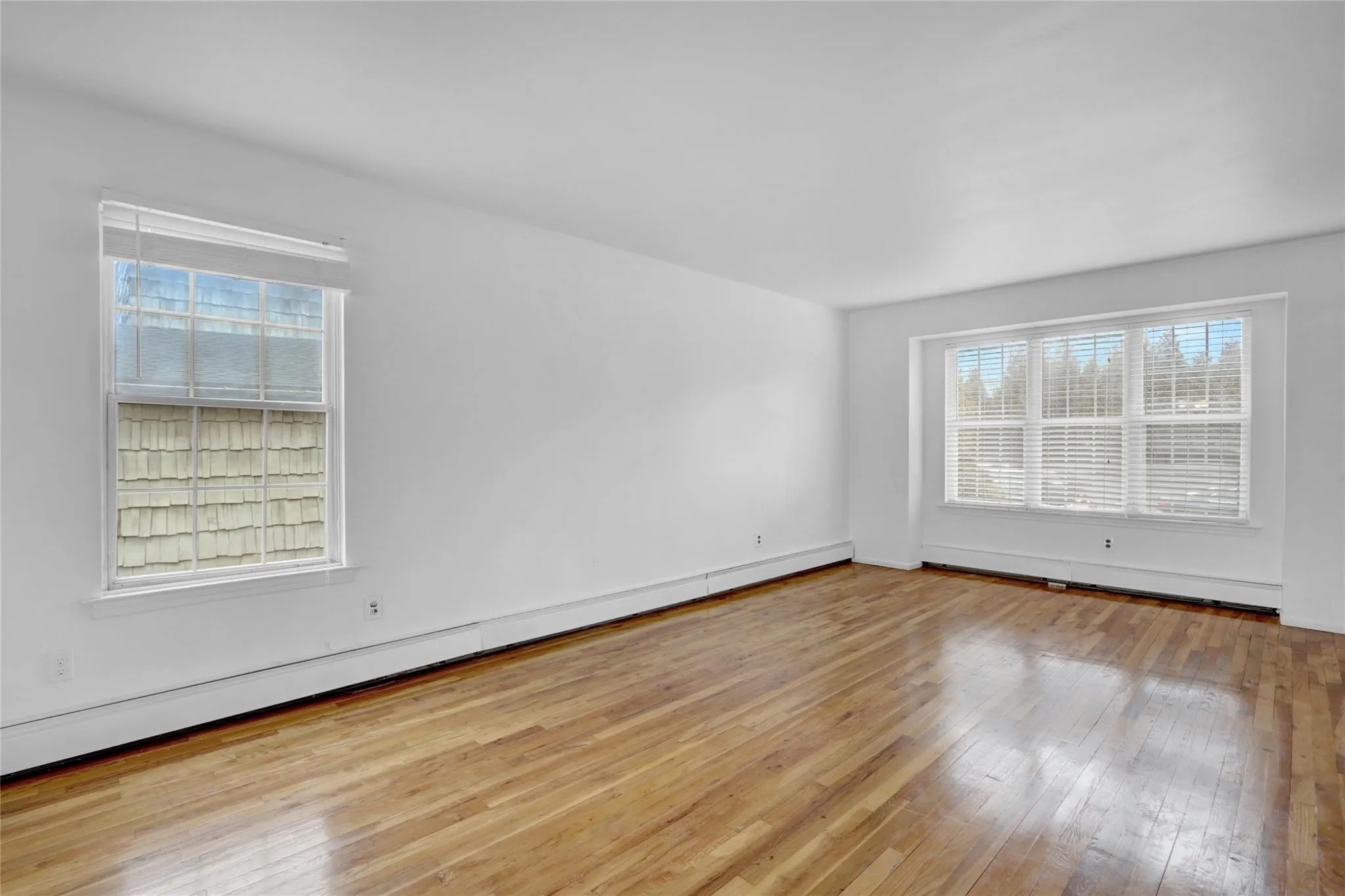 Unfurnished room featuring hardwood / wood-style floors and baseboard heating Unfurnished room featuring hardwood / wood-style floors and baseboard heating