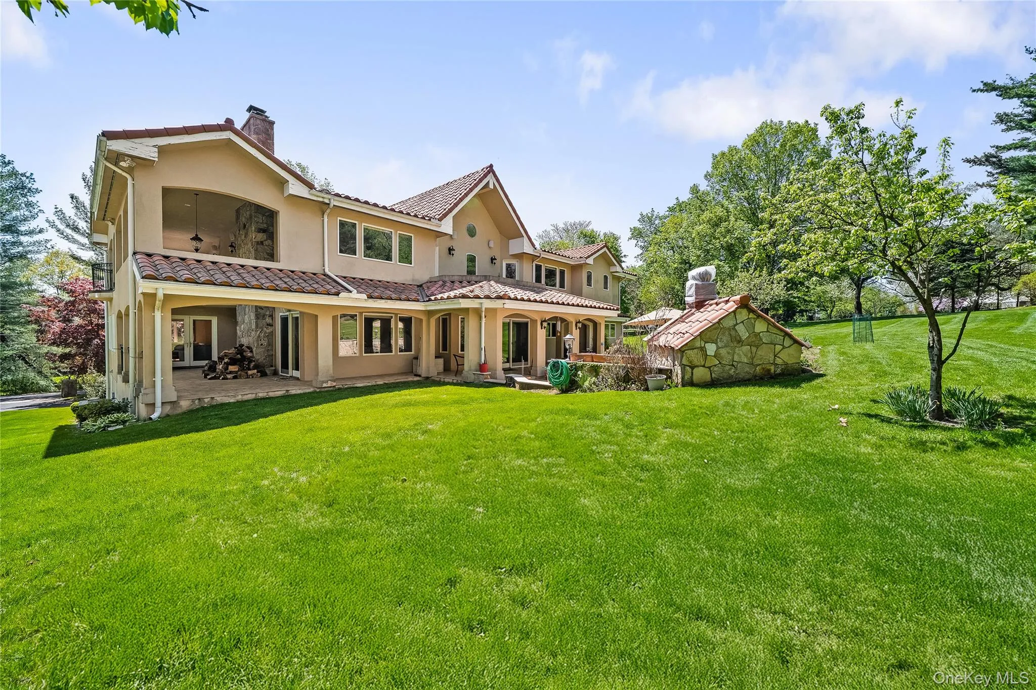 Back of property with a chimney, stucco siding, a lawn, and a tile roof Back of property with a chimney, stucco siding, a lawn, and a tile roof