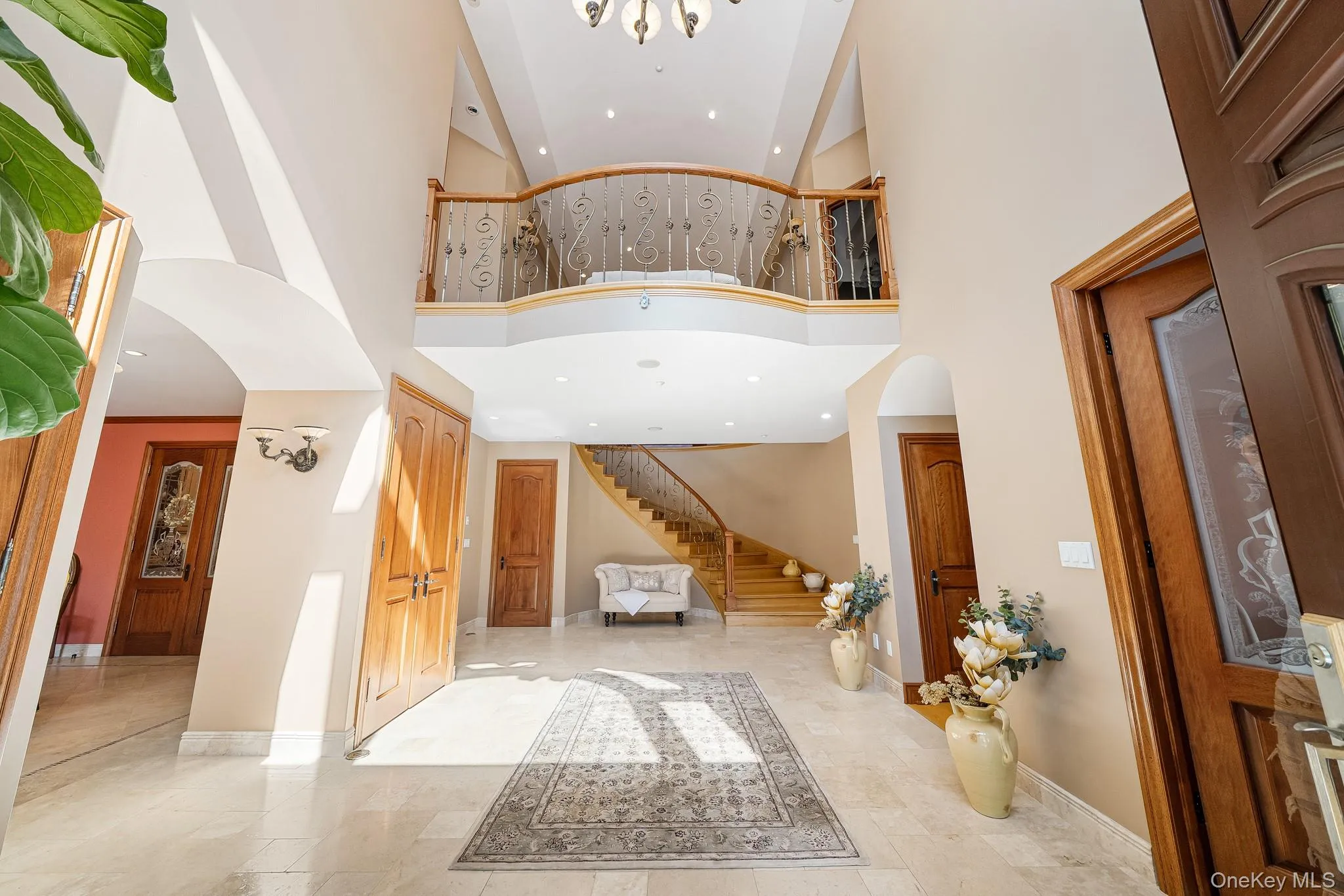 Entrance foyer with arched walkways, high vaulted ceiling, stairs, and recessed lighting Entrance foyer with arched walkways, high vaulted ceiling, stairs, and recessed lighting