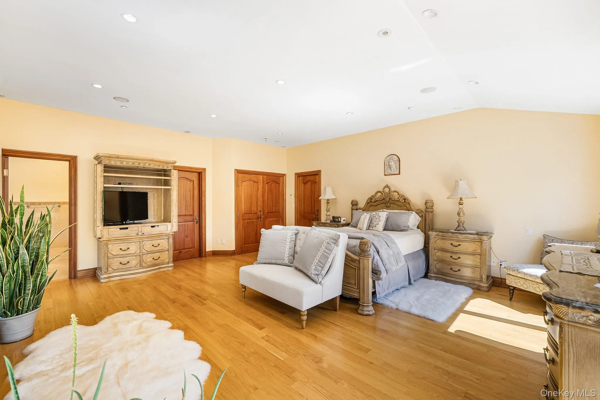 Bedroom featuring light wood finished floors, vaulted ceiling, and recessed lighting Bedroom featuring light wood finished floors, vaulted ceiling, and recessed lighting