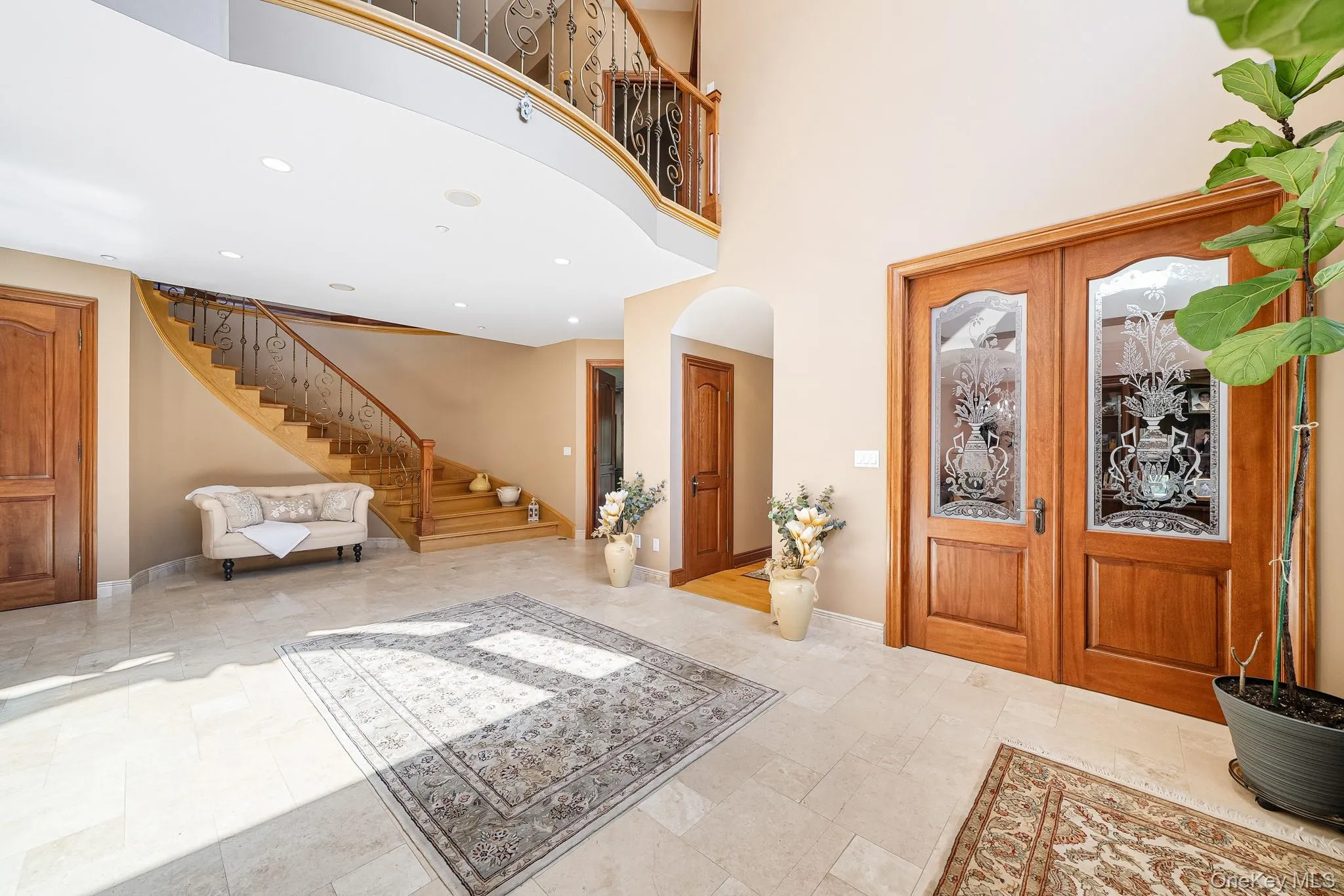 Foyer entrance featuring stairs, french doors, arched walkways, a towering ceiling, and recessed lighting Foyer entrance featuring stairs, french doors, arched walkways, a towering ceiling, and recessed lighting