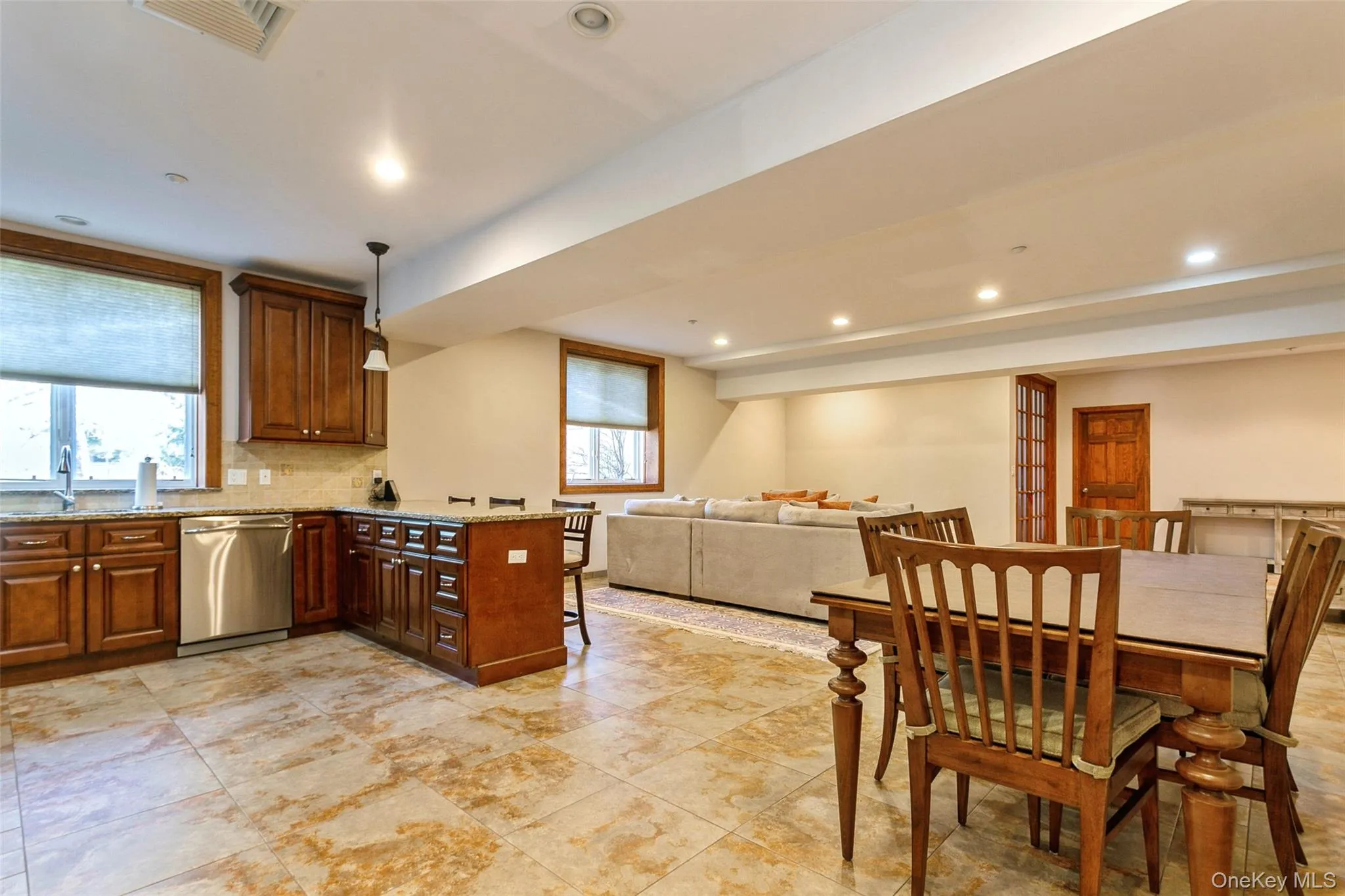 Kitchen with stainless steel dishwasher, a peninsula, light stone counters, recessed lighting, and decorative backsplash Kitchen with stainless steel dishwasher, a peninsula, light stone counters, recessed lighting, and decorative backsplash