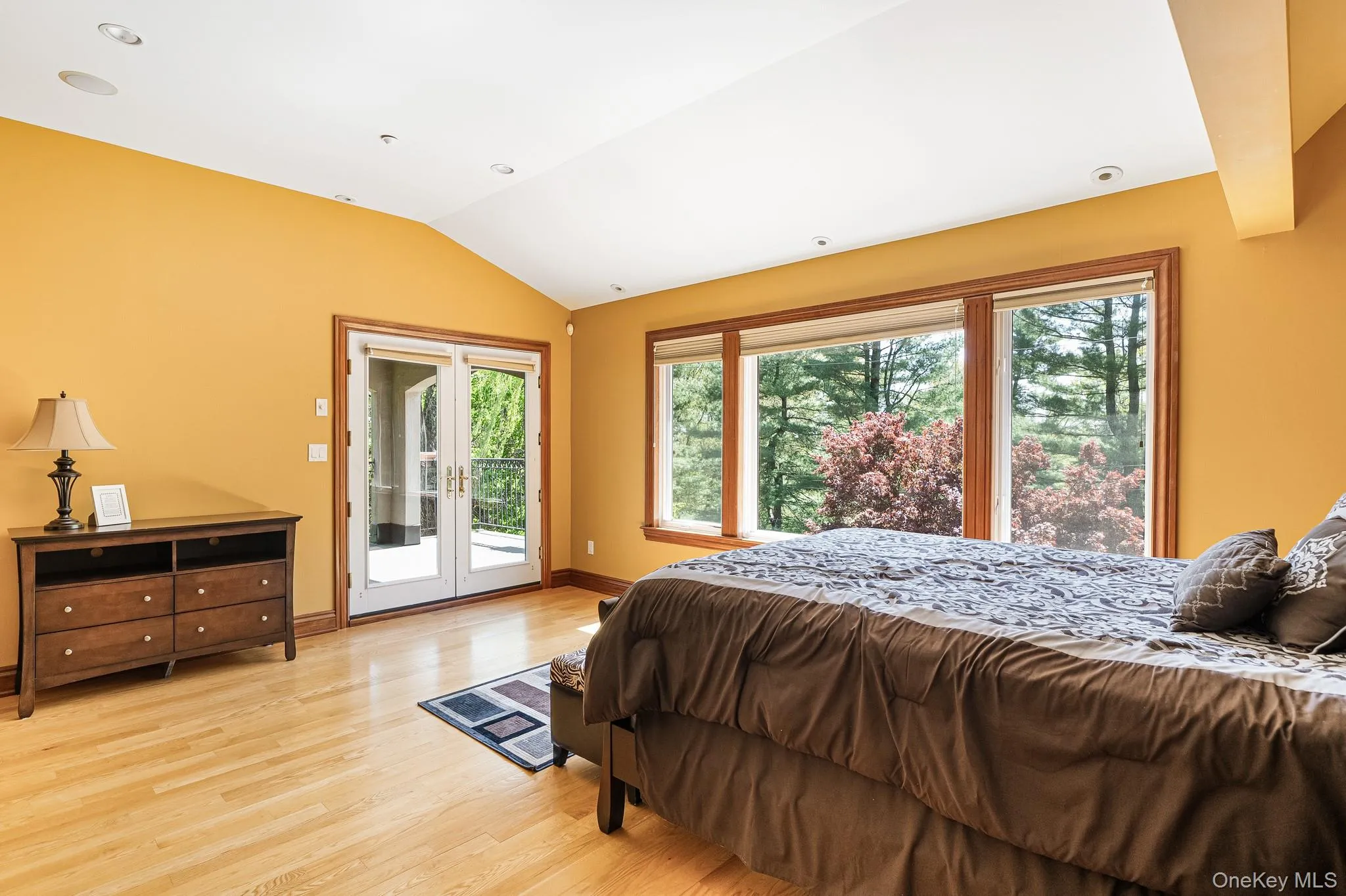Bedroom with vaulted ceiling, access to exterior, light wood finished floors, and french doors Bedroom with vaulted ceiling, access to exterior, light wood finished floors, and french doors
