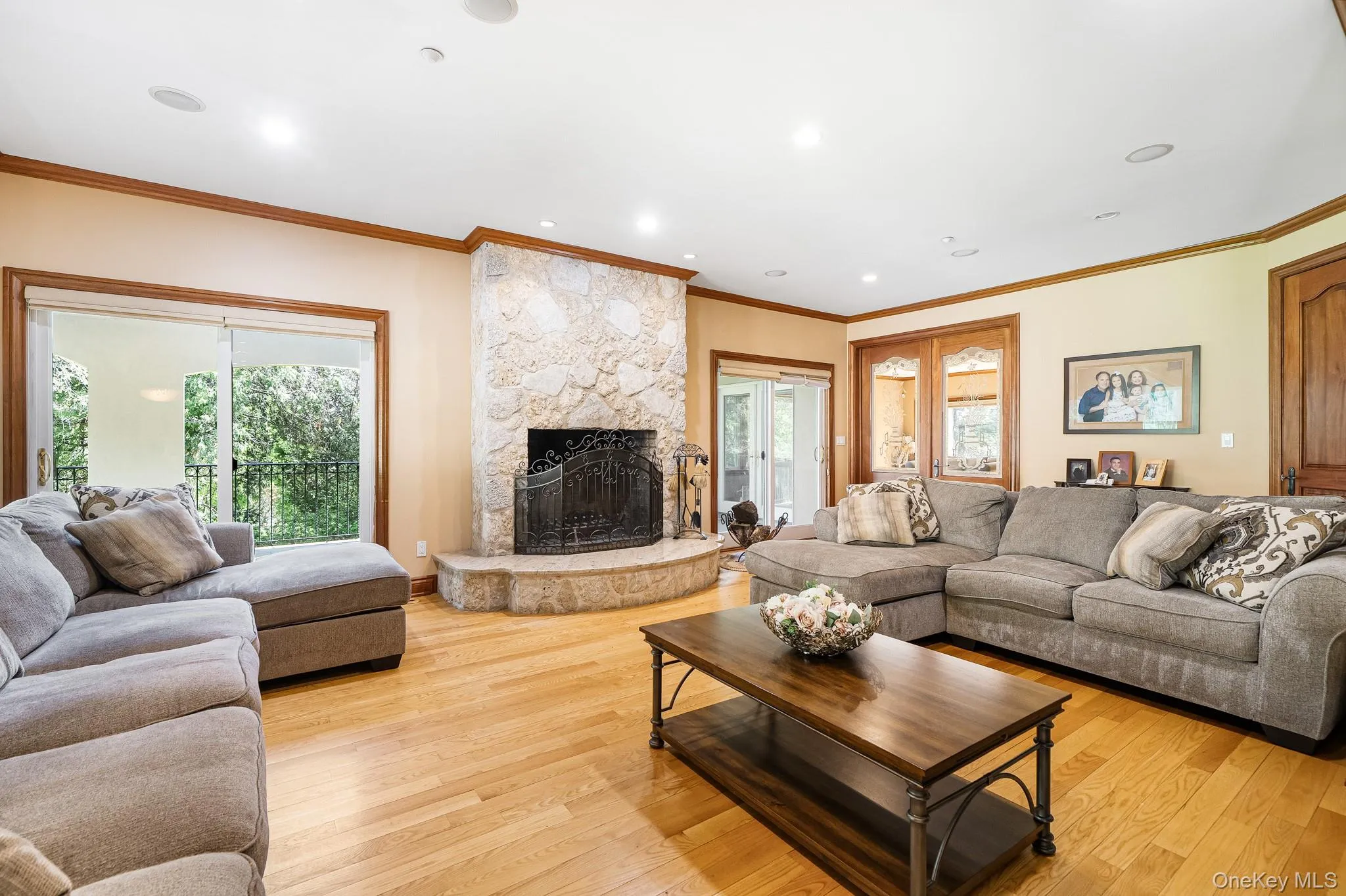 Living area with plenty of natural light, a fireplace, ornamental molding, light wood-style floors, and recessed lighting Living area with plenty of natural light, a fireplace, ornamental molding, light wood-style floors, and recessed lighting
