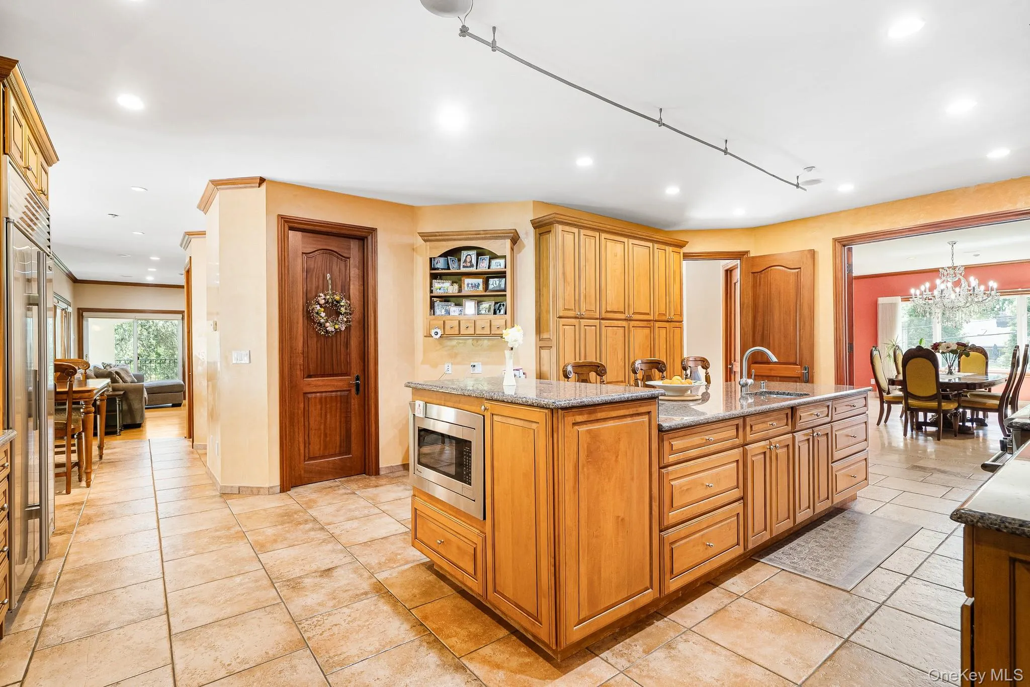 Kitchen featuring stainless steel microwave, recessed lighting, light stone counters, an island with sink, and a chandelier Kitchen featuring stainless steel microwave, recessed lighting, light stone counters, an island with sink, and a chandelier