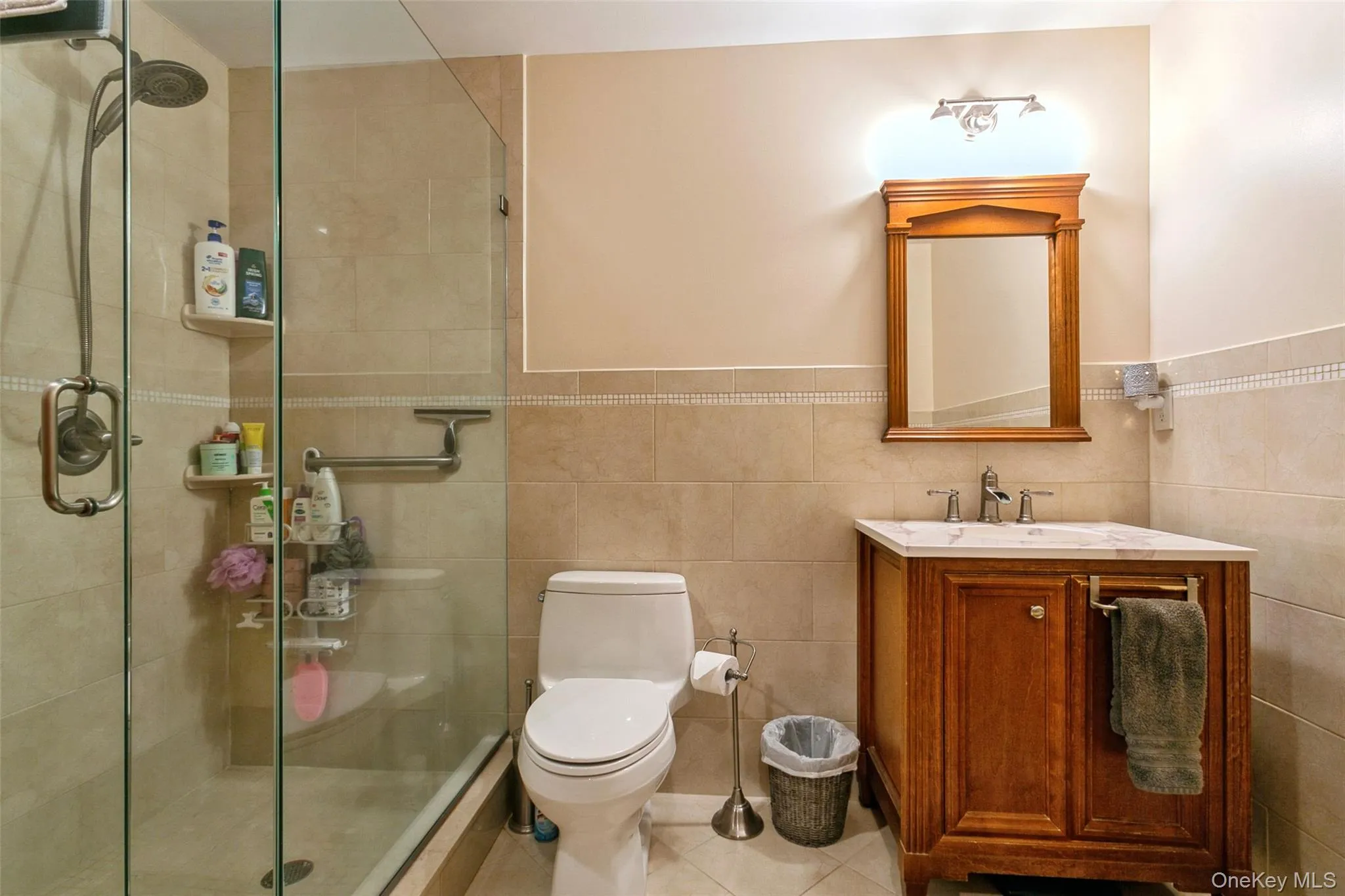 Bathroom featuring tile walls, vanity, a stall shower, and tile patterned floors Bathroom featuring tile walls, vanity, a stall shower, and tile patterned floors