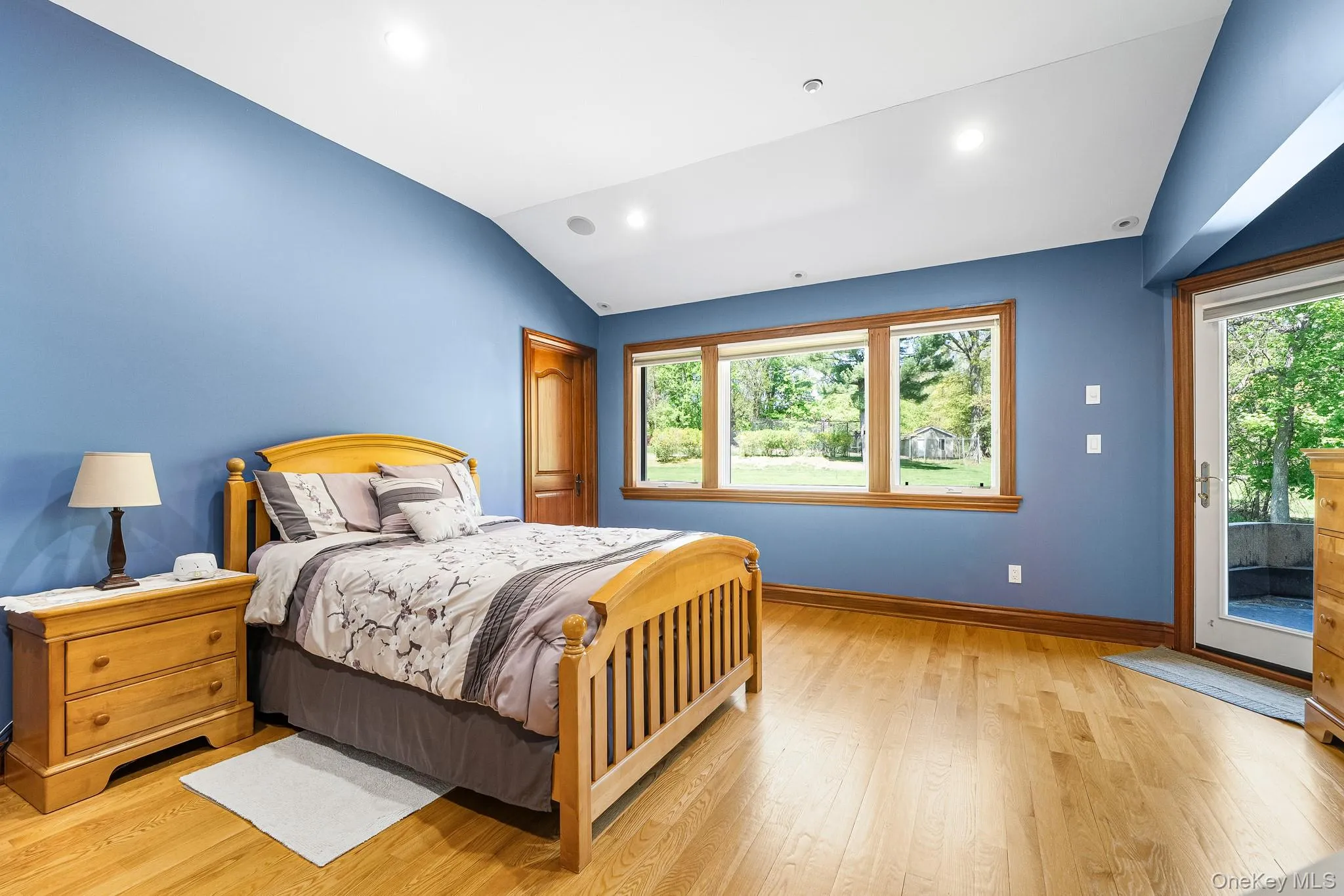 Bedroom featuring access to exterior, light wood finished floors, and lofted ceiling Bedroom featuring access to exterior, light wood finished floors, and lofted ceiling
