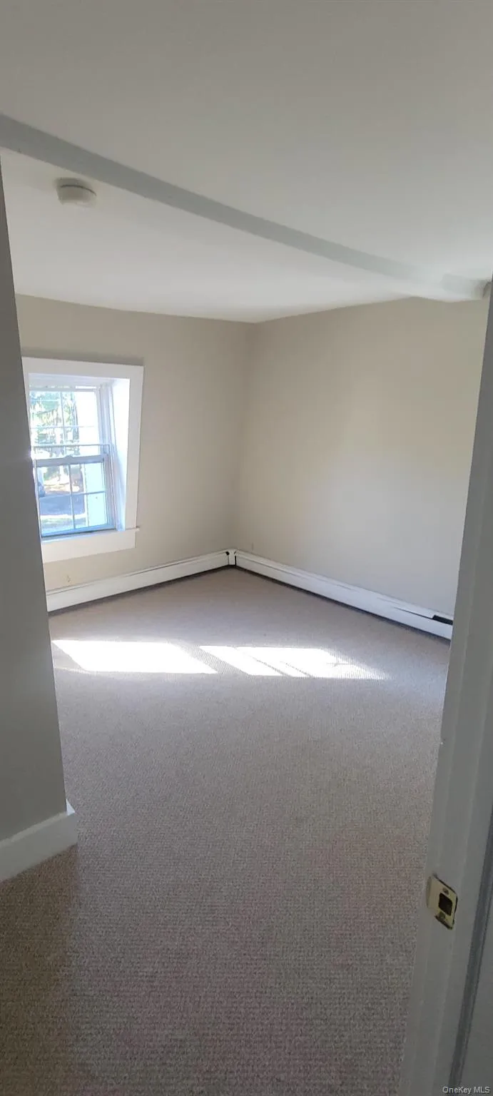 Carpeted empty room with baseboards and a baseboard heating unit Carpeted empty room with baseboards and a baseboard heating unit