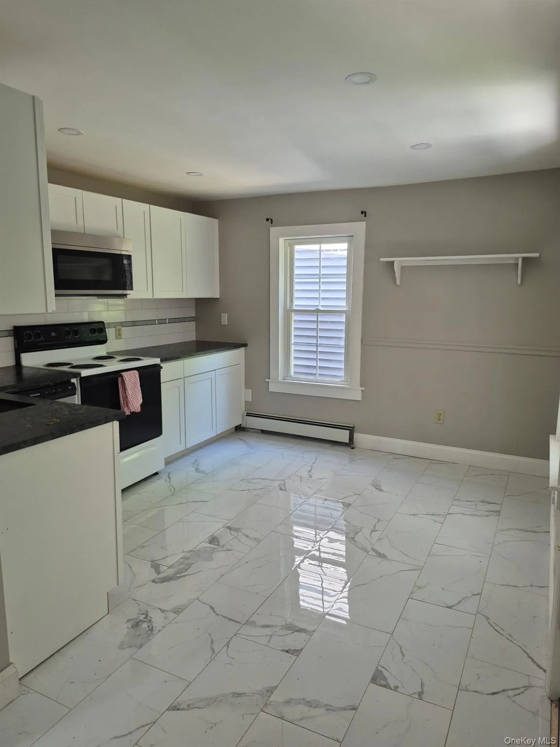 Kitchen featuring light marble finish floors, electric stove, backsplash, white cabinets, and recessed lighting Kitchen featuring light marble finish floors, electric stove, backsplash, white cabinets, and recessed lighting