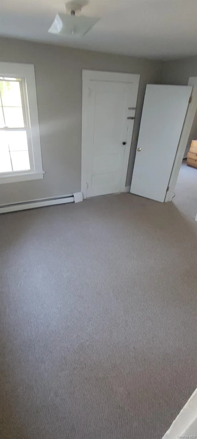 Carpeted spare room featuring a baseboard radiator and baseboards Carpeted spare room featuring a baseboard radiator and baseboards